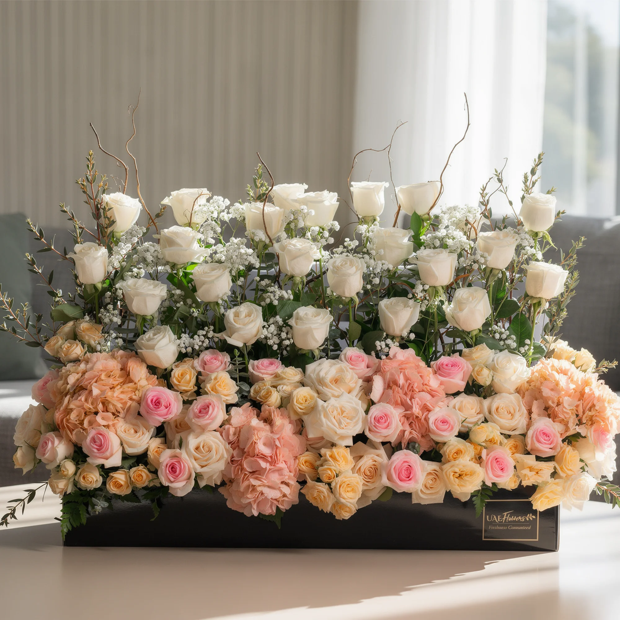 Arrangement of 30 White roses, 20 pink roses, 4 pink hydrangeas and 10 peach spray roses with green fillers and baby's breath in a long black box.