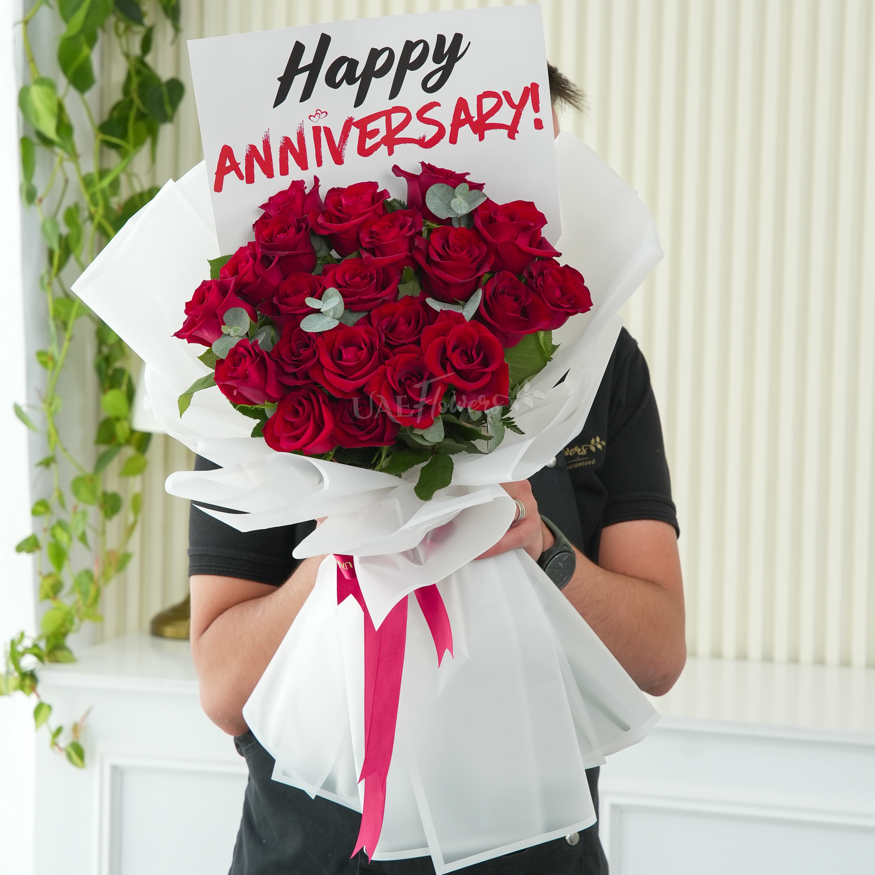 Bouquet of 15 red roses with green fillers in white wrapping.