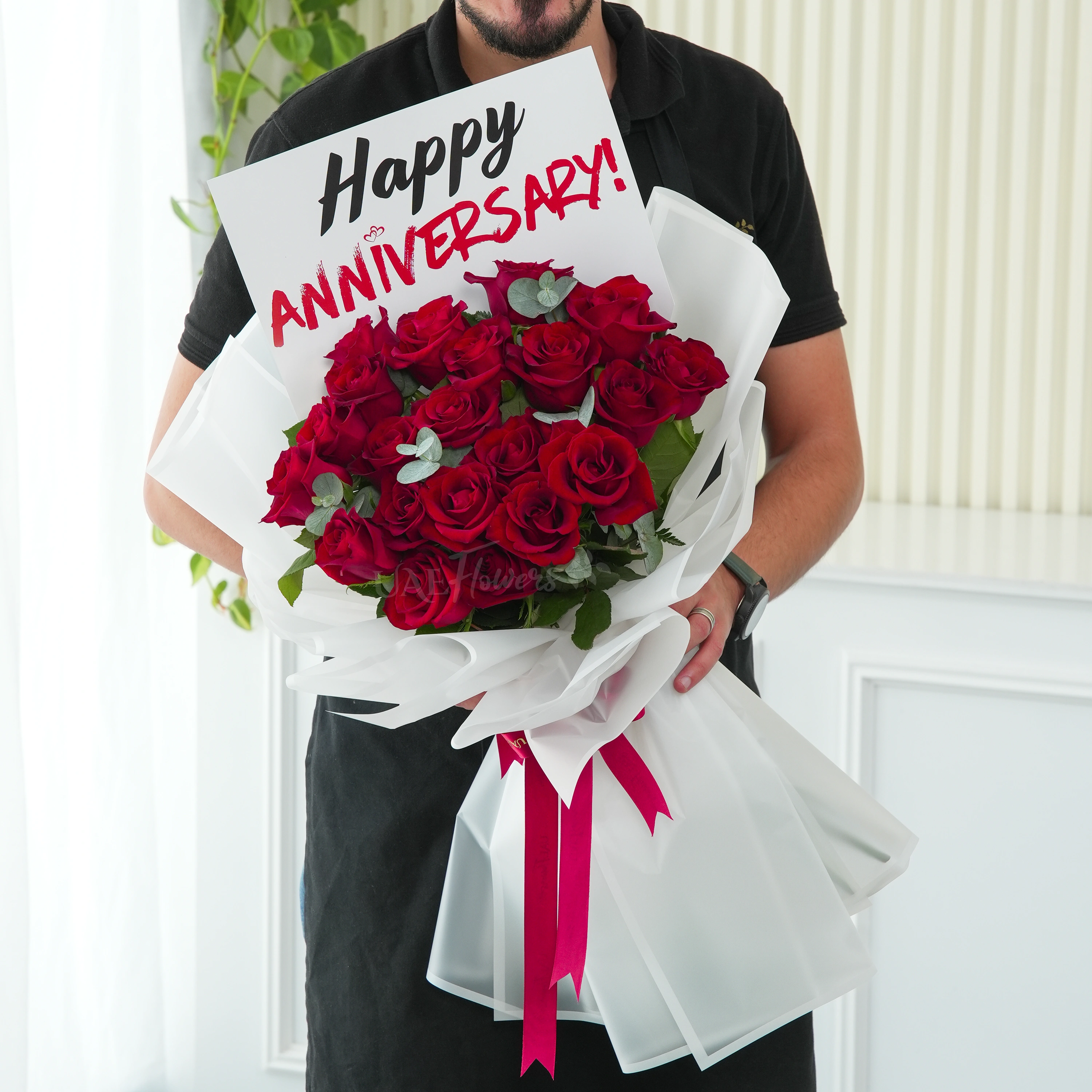 Bouquet of 15 red roses with green fillers in white wrapping.