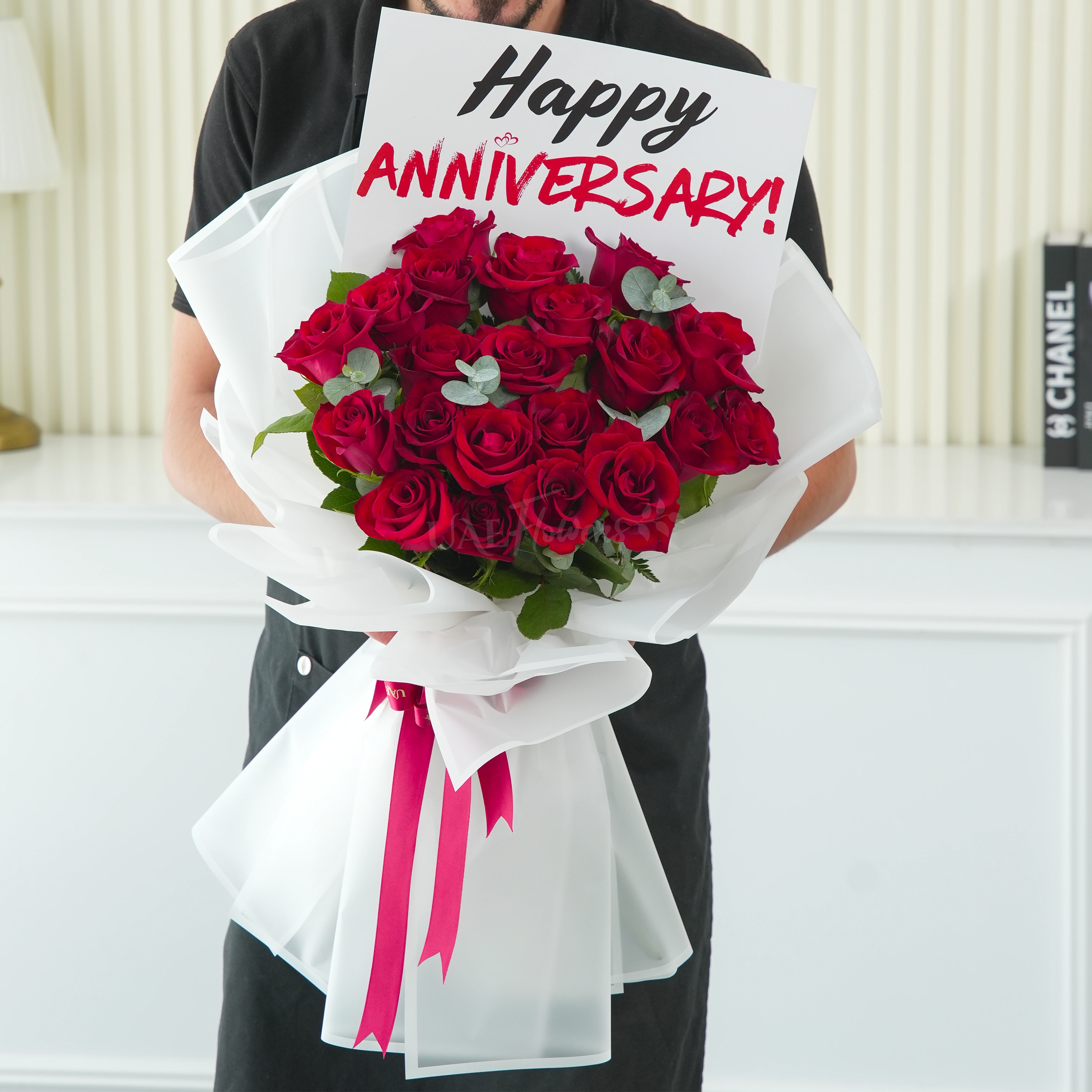 Bouquet of 15 red roses with green fillers in white wrapping.