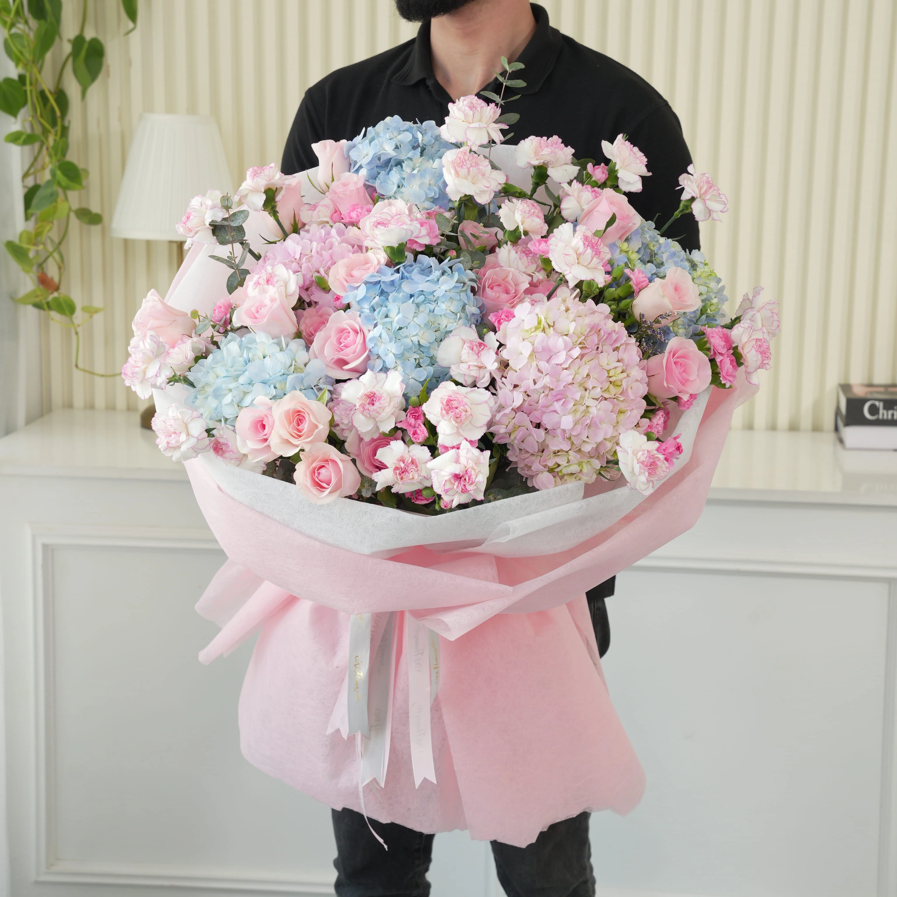 Bouquet of 4 blue hydrangeas, 2 pink hydrangeas, 30 pink roses, 30 pink carnations and 10 pink spray carnations with green fillers in pink wrapping.