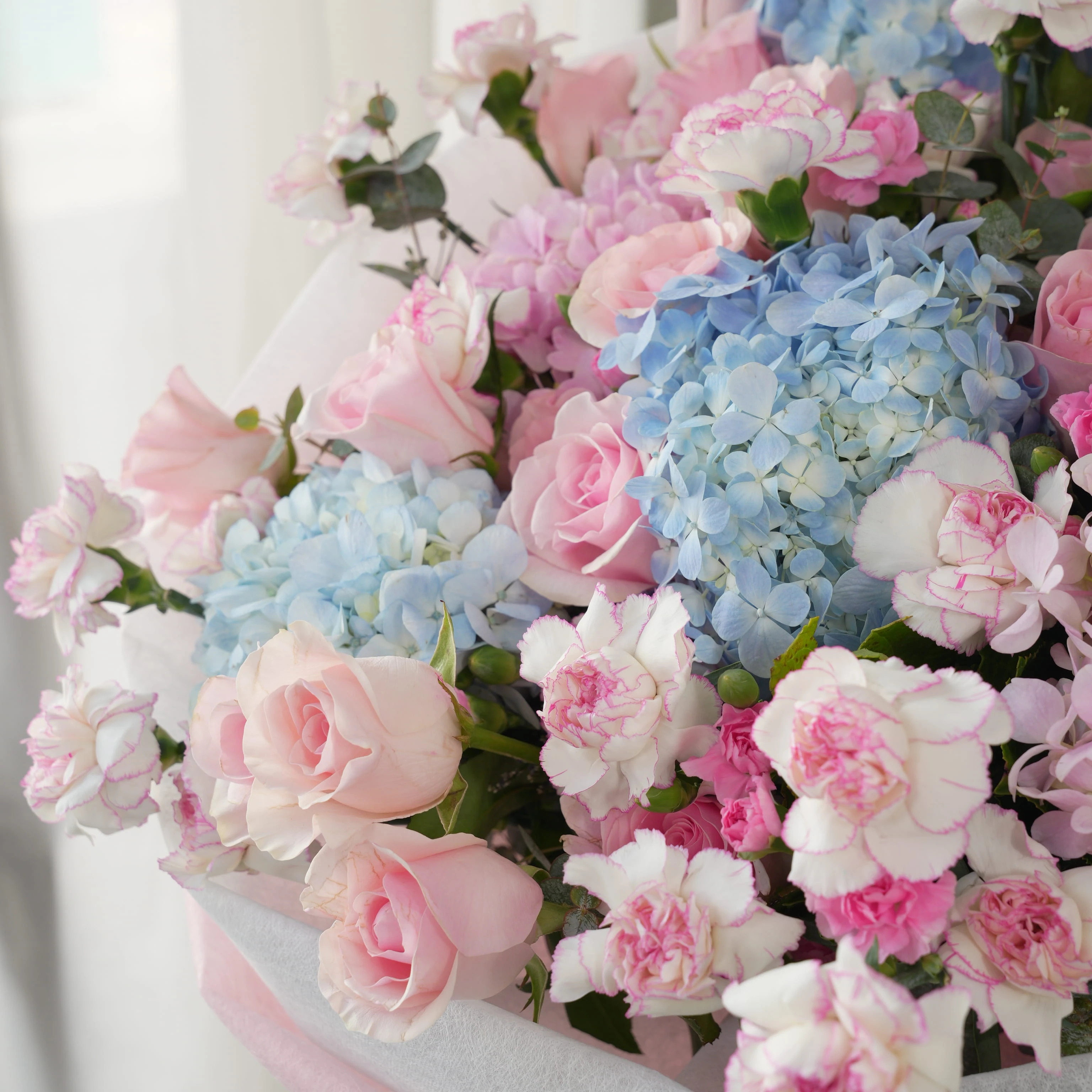 Bouquet of 4 blue hydrangeas, 2 pink hydrangeas, 30 pink roses, 30 pink carnations and 10 pink spray carnations with green fillers in pink wrapping.
