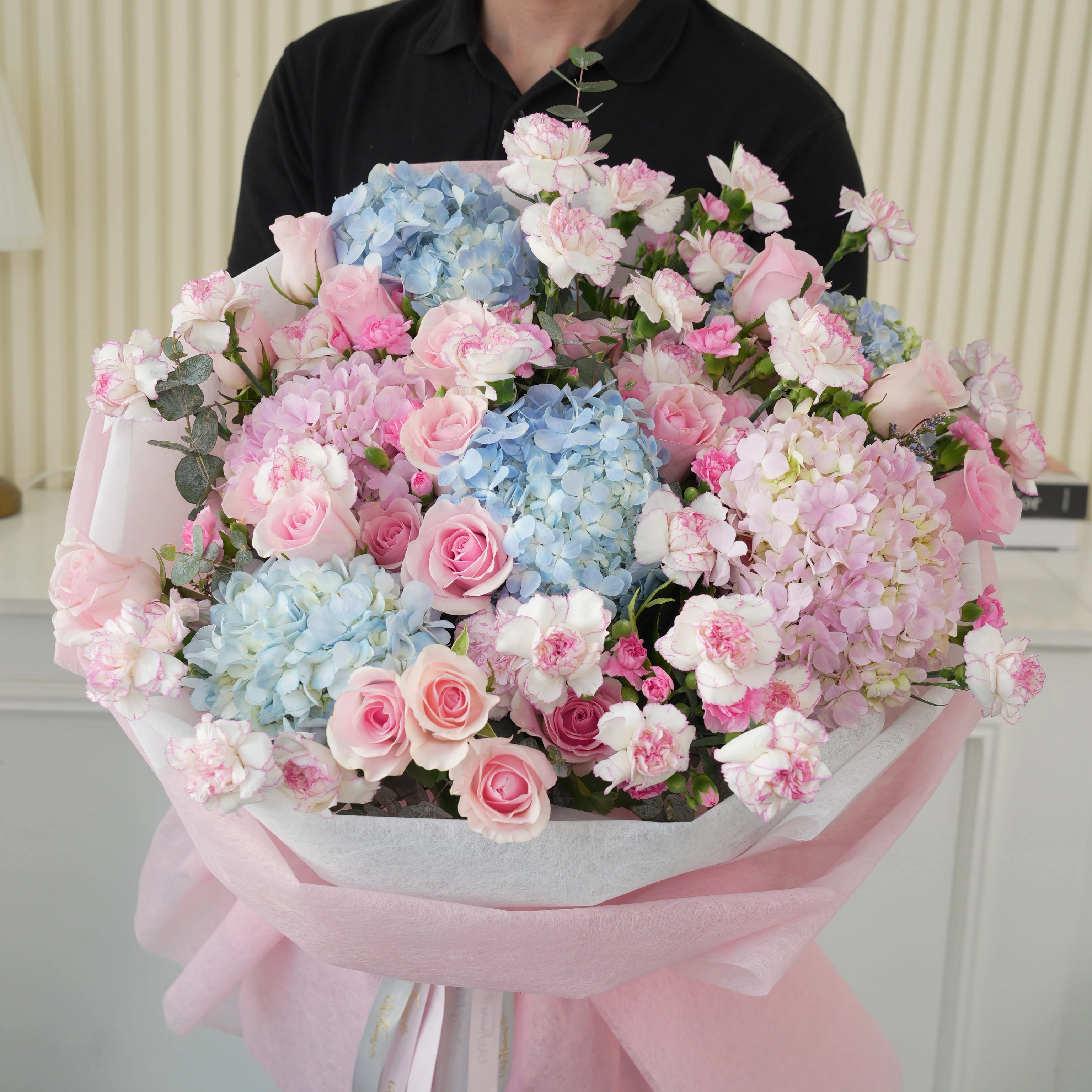 Bouquet of 4 blue hydrangeas, 2 pink hydrangeas, 30 pink roses, 30 pink carnations and 10 pink spray carnations with green fillers in pink wrapping.