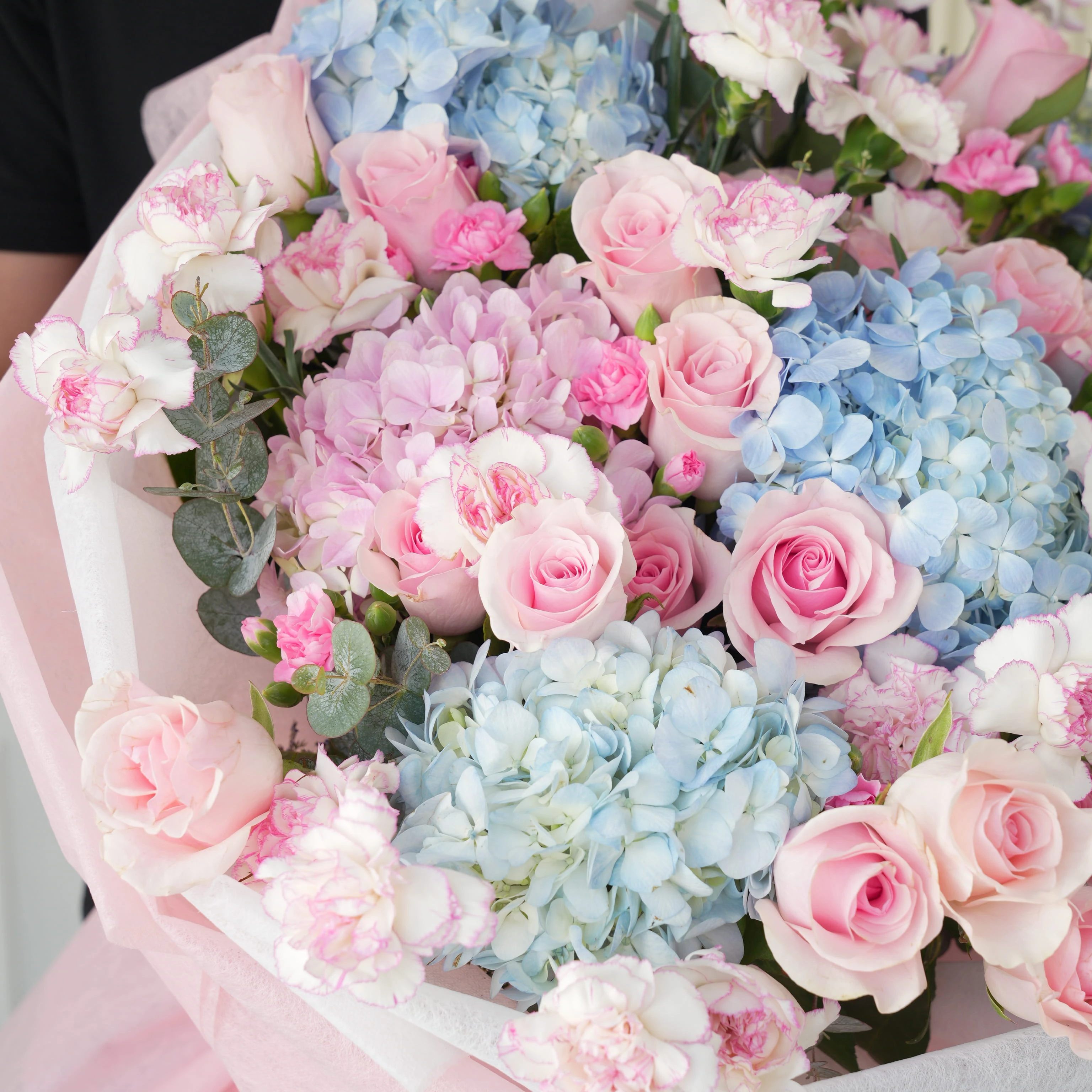 Bouquet of 4 blue hydrangeas, 2 pink hydrangeas, 30 pink roses, 30 pink carnations and 10 pink spray carnations with green fillers in pink wrapping.