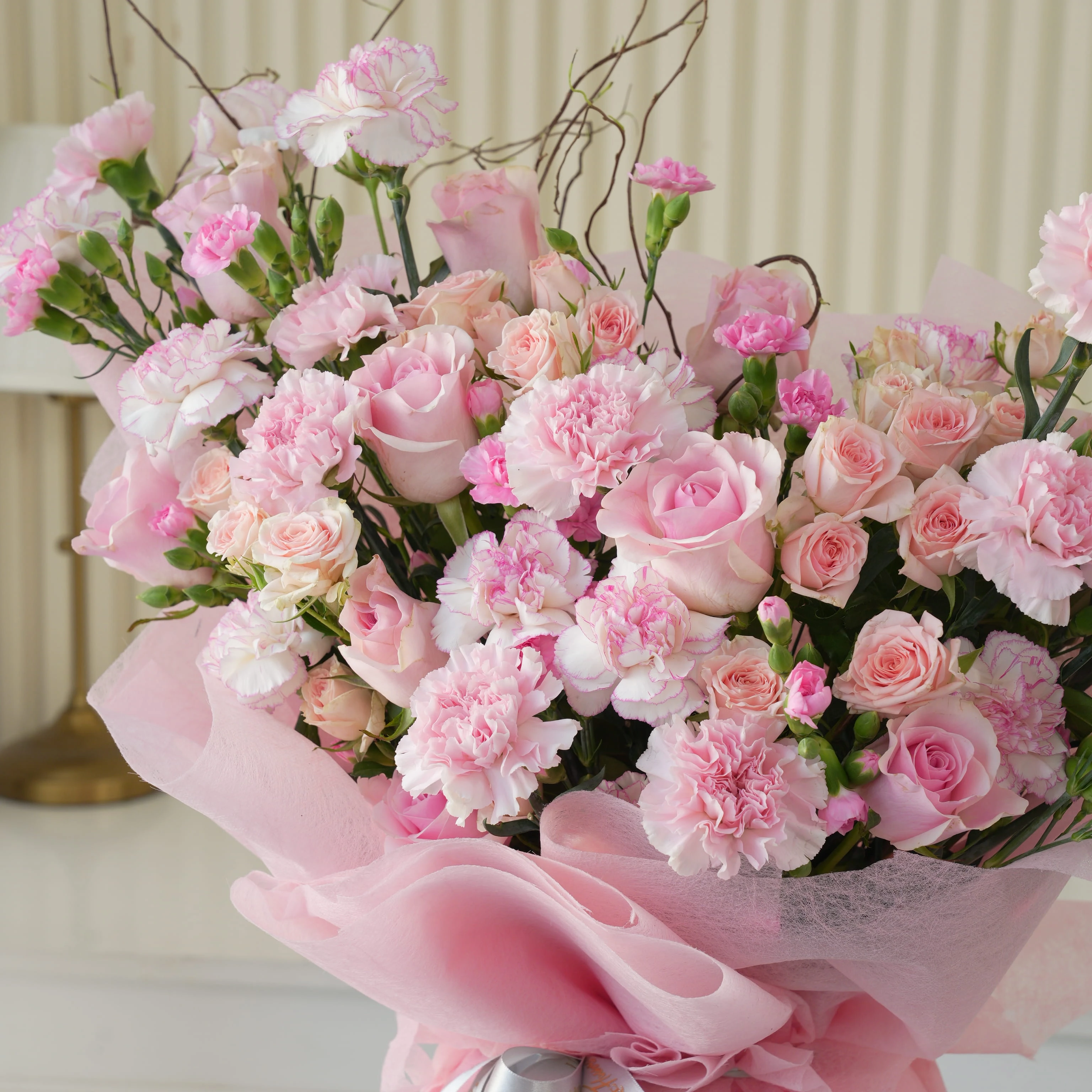 Bouquet of 12 pink roses, 20 pink carnations and 5 pink spray roses with green fillers in pink wrapping.