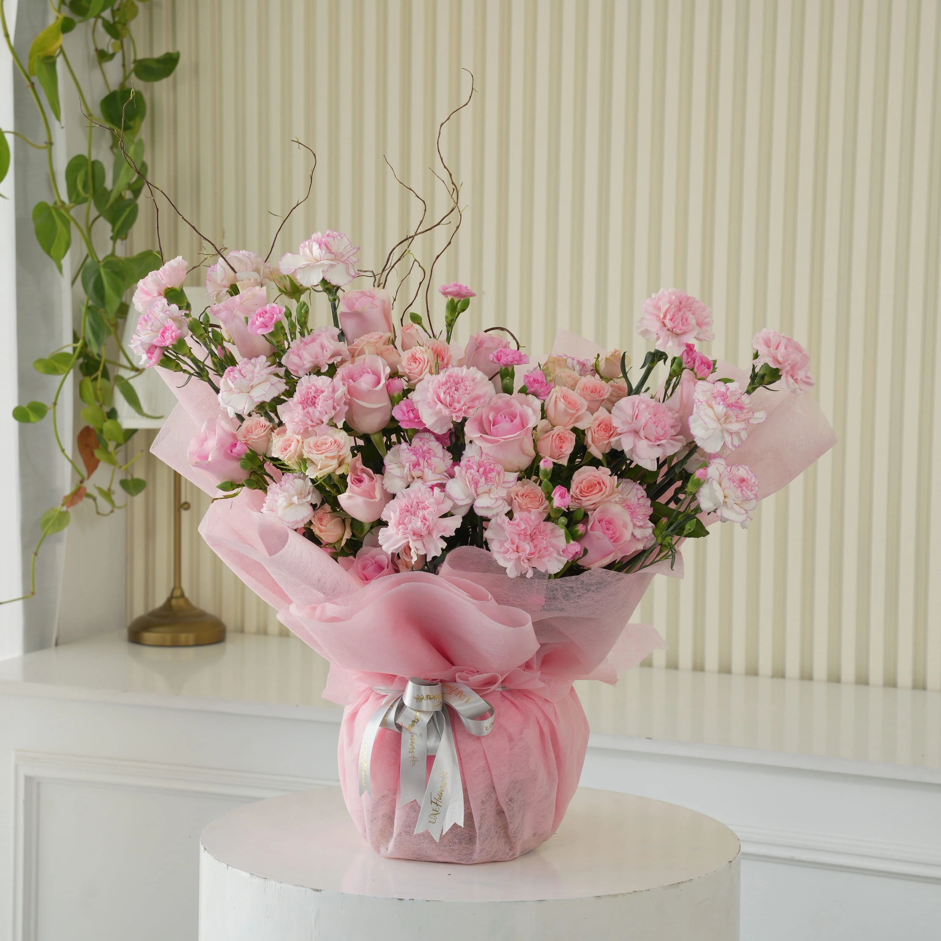 Bouquet of 12 pink roses, 20 pink carnations and 5 pink spray roses with green fillers in pink wrapping.
