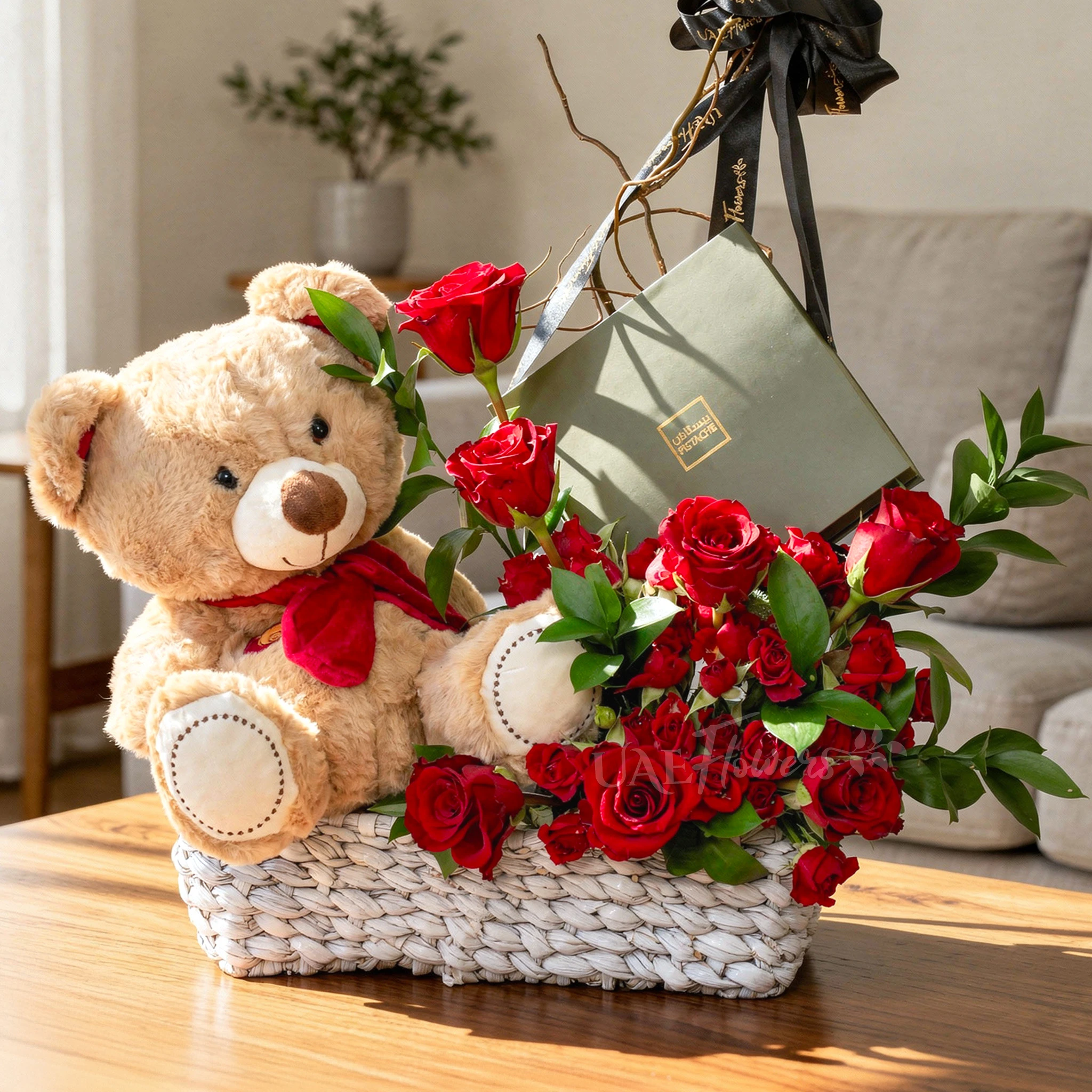 Basket arrangement of 7 red roses, 5 red spray roses, small brown teddy bear and 16 Pcs Pistache Classic Selection Chocolate Box with green fillers.