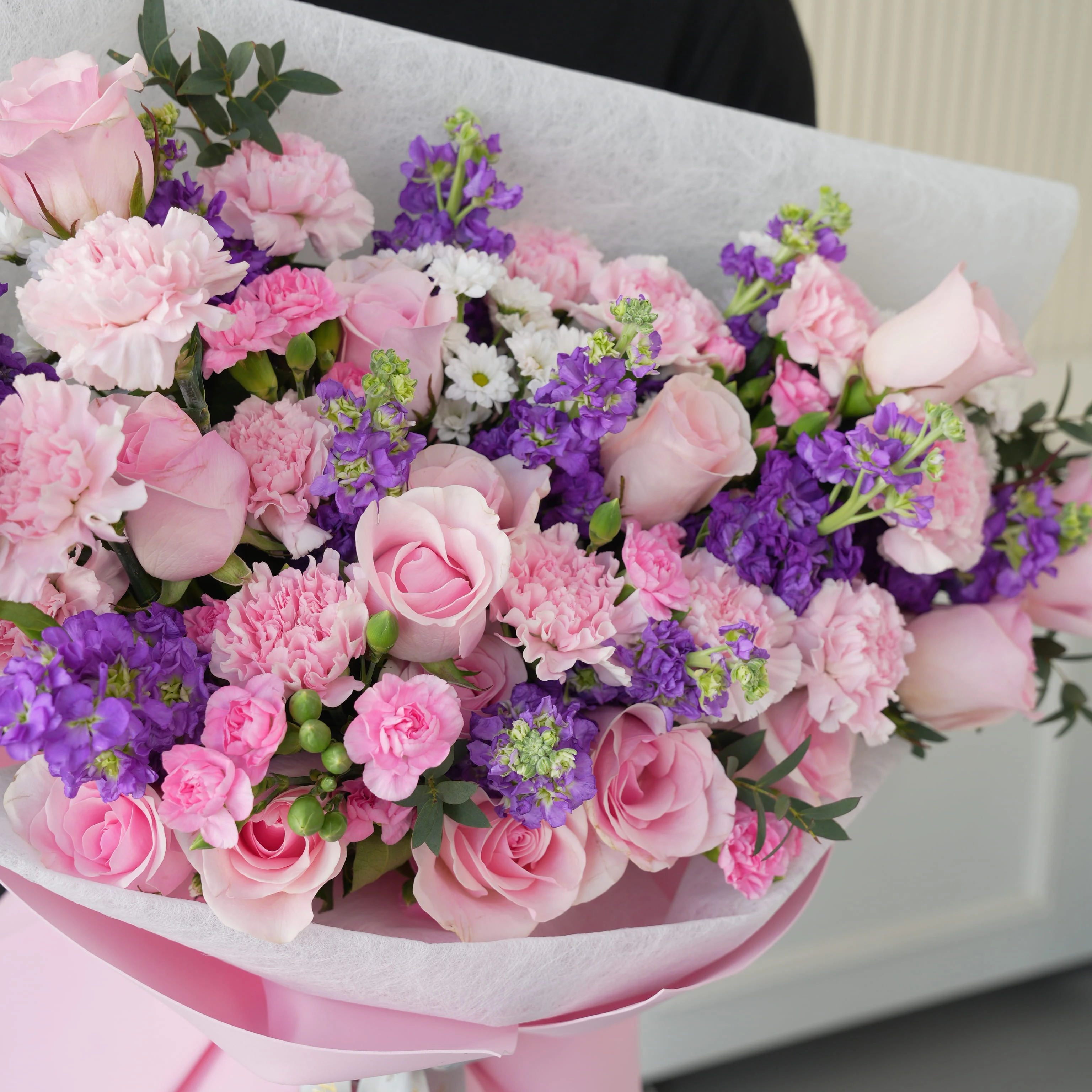 Bouquet of 10 purple matthiola, 12 pink roses, 10 pink carnations, 5 pink spray carnations, 5 white chrysanthemums with green fillers in pink wrapping.
