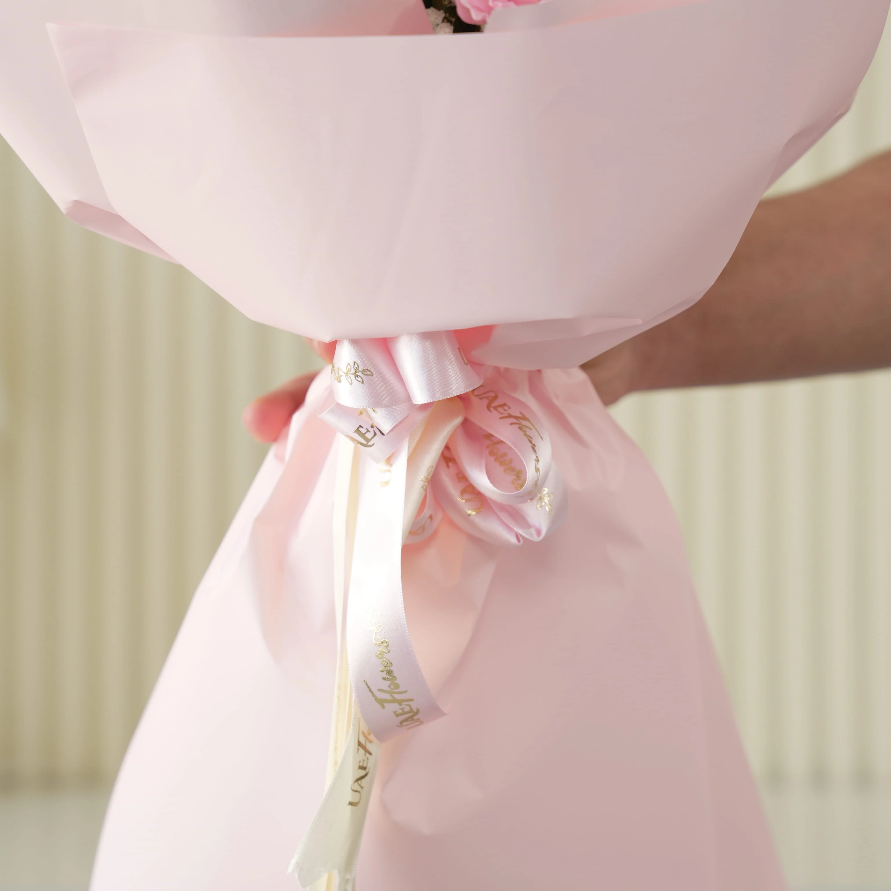 Bouquet of 7 pink roses, 6 pink carnations, 2 white chrysanthemums with green fillers in pink wrapping.