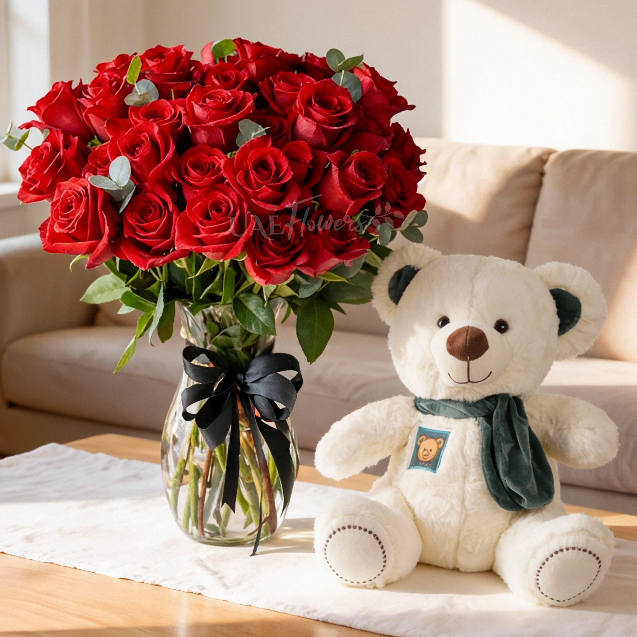 30 red roses with green fillers in a glass vase and small white teddy bear.