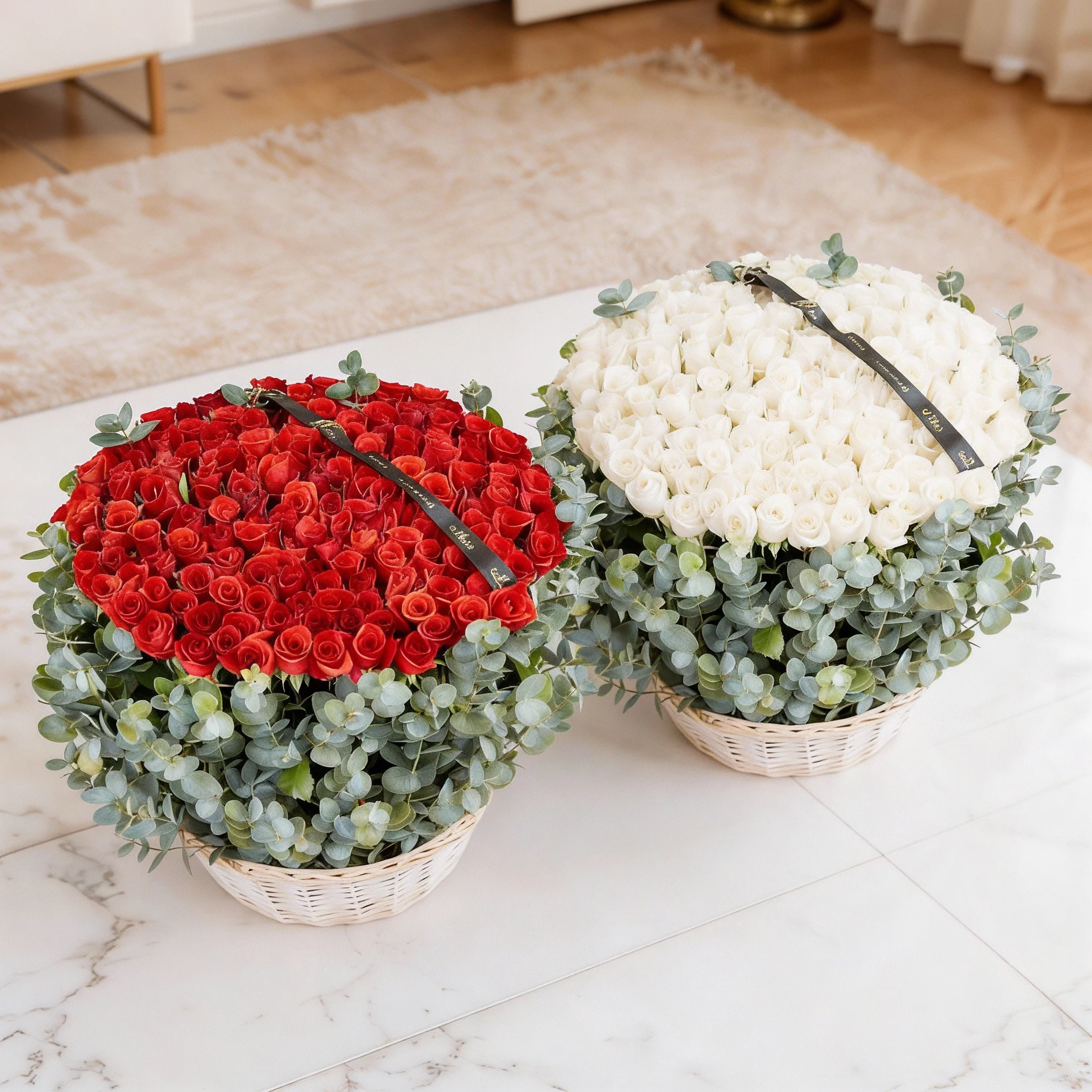 Two separate arrangements of 150 red roses and 150 white roses, each beautifully arranged with eucalyptus leaves in a basket.