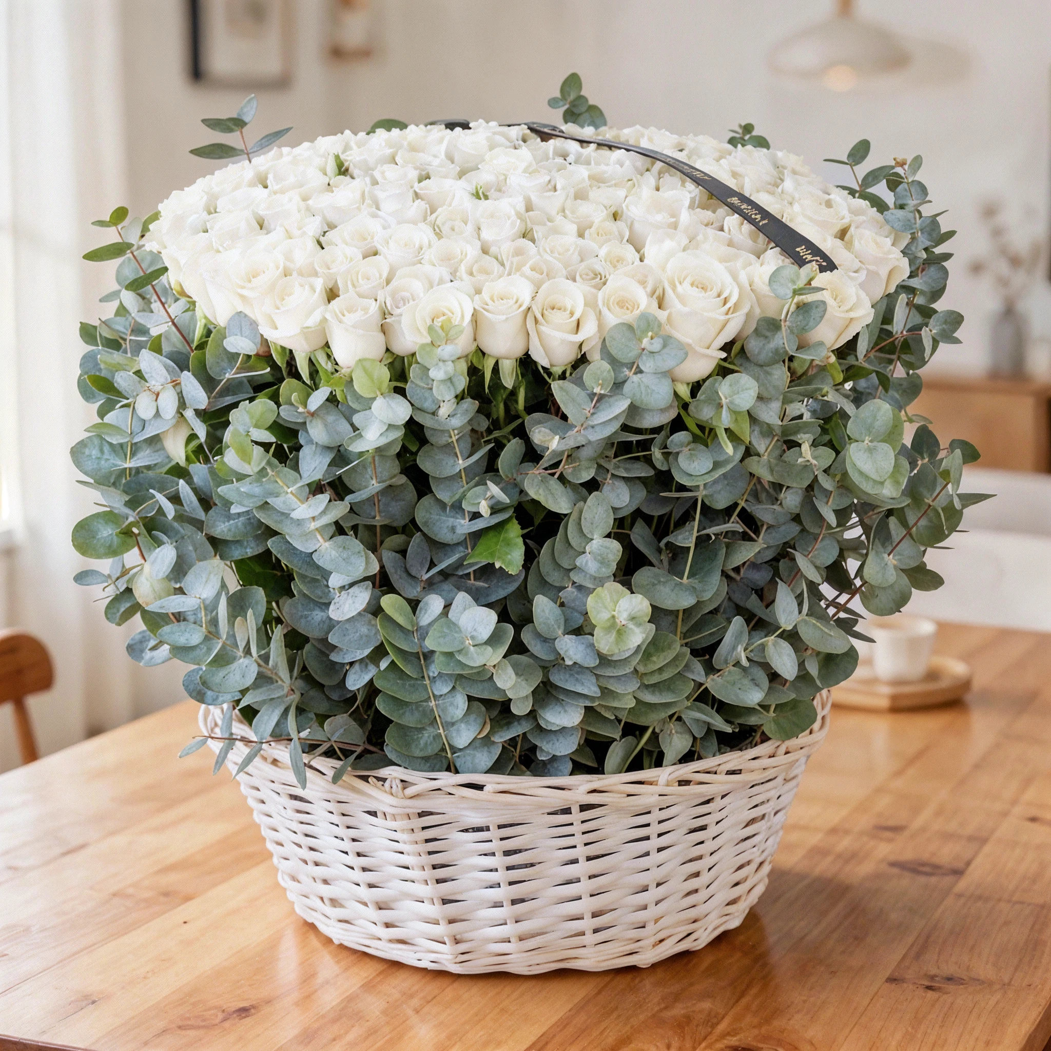 150 white roses with eucalyptus leaf in a basket.