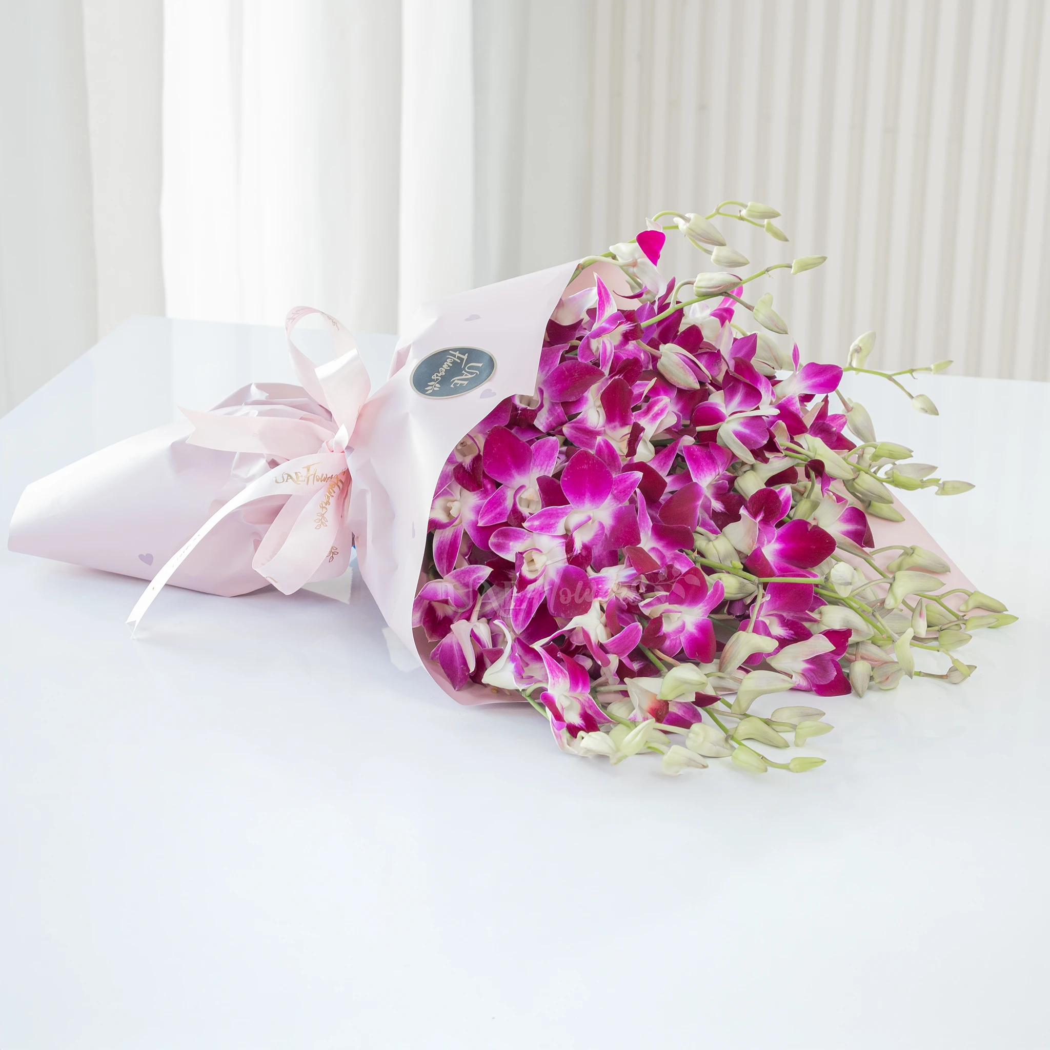 Bouquet of 20 purple orchids with fillers in a pink wrapping paper.