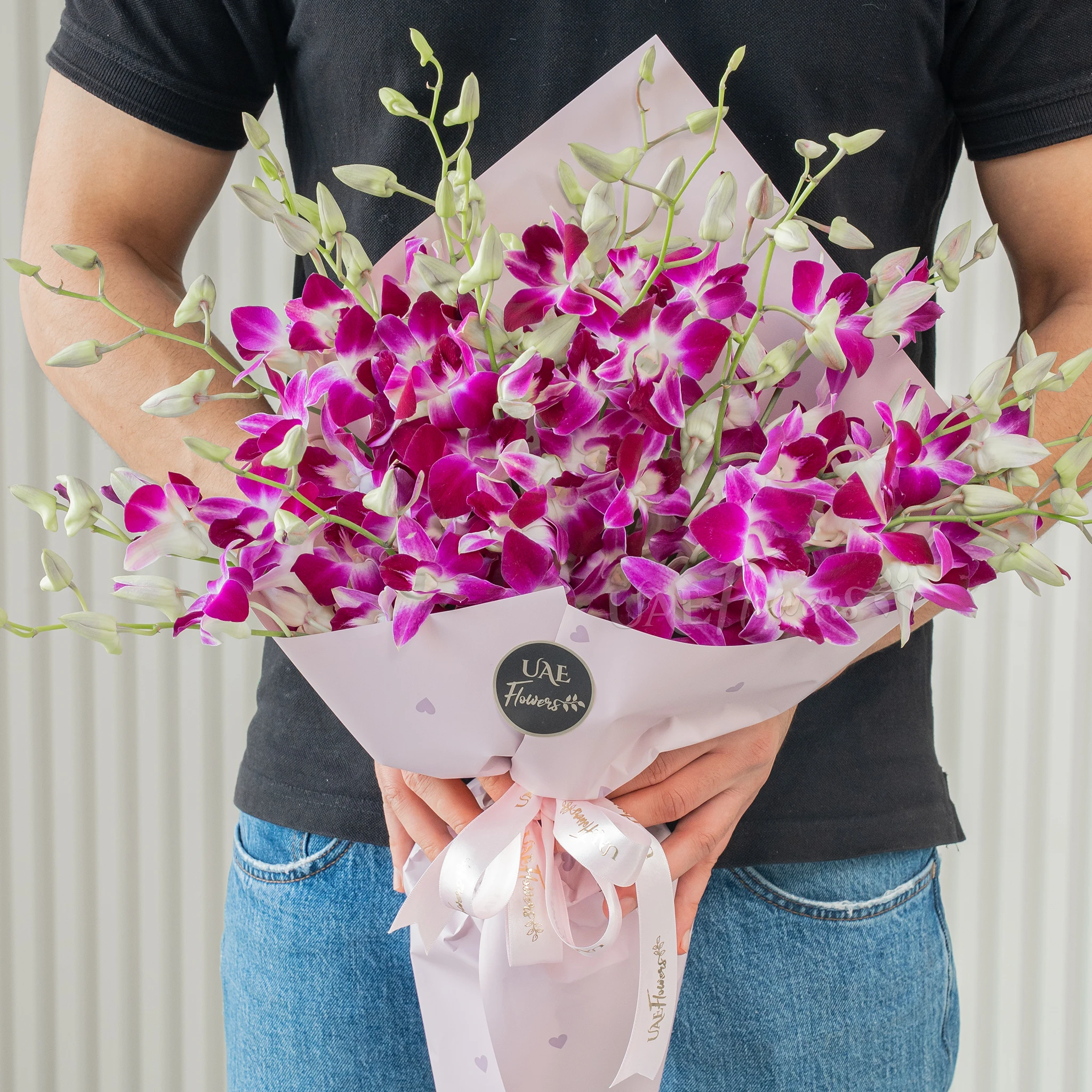 Bouquet of 20 purple orchids with fillers in a pink wrapping paper.