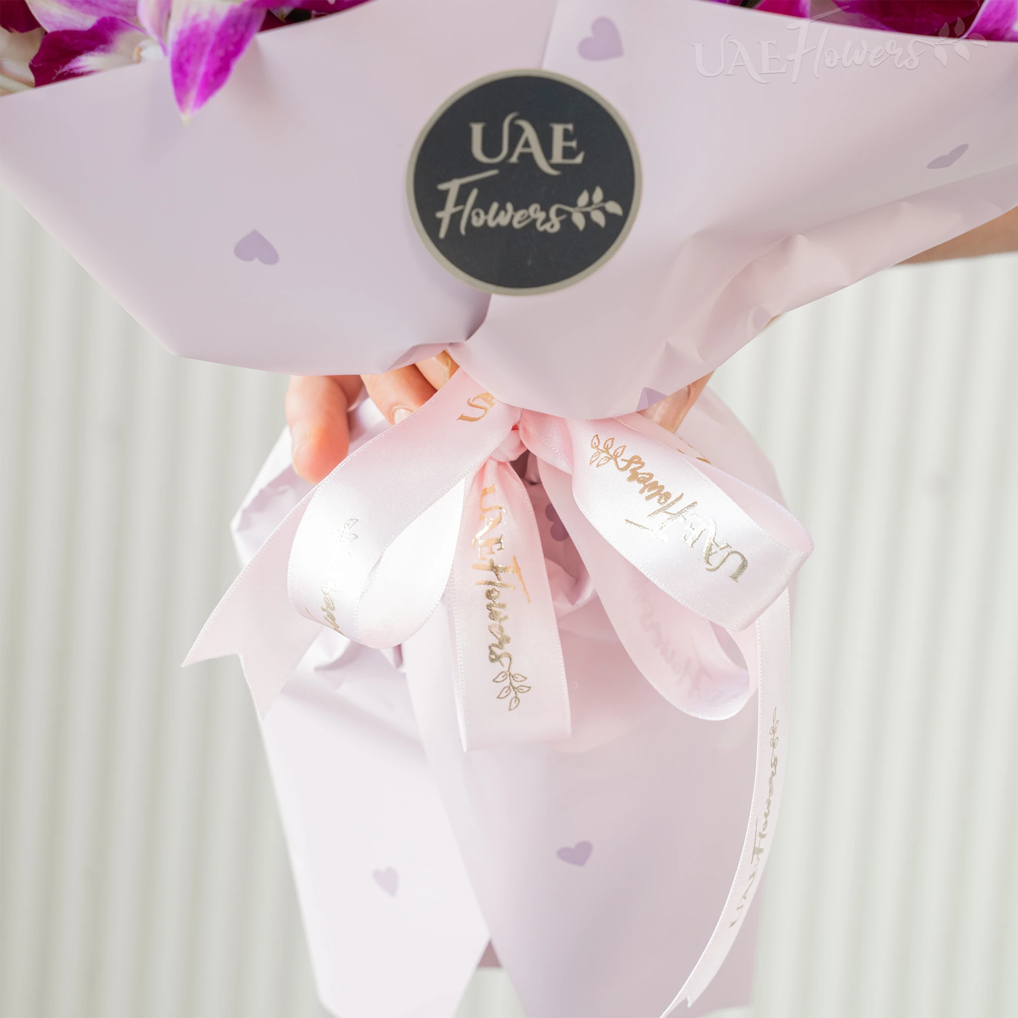 Bouquet of 20 purple orchids with fillers in a pink wrapping paper.