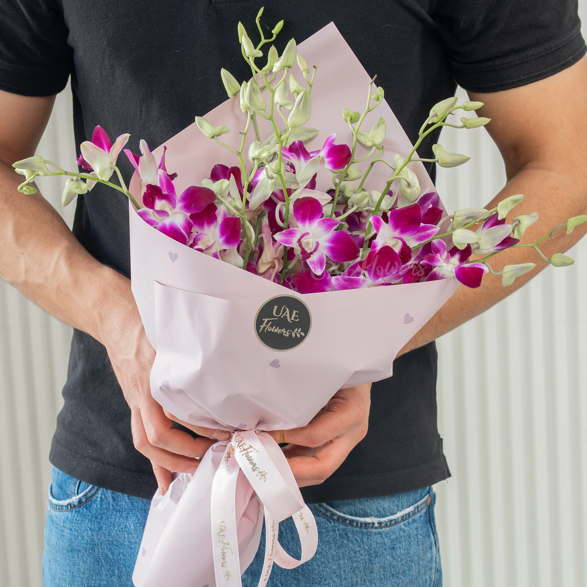 Bouquet of 10 purple orchids with fillers in a pink wrapping paper.
