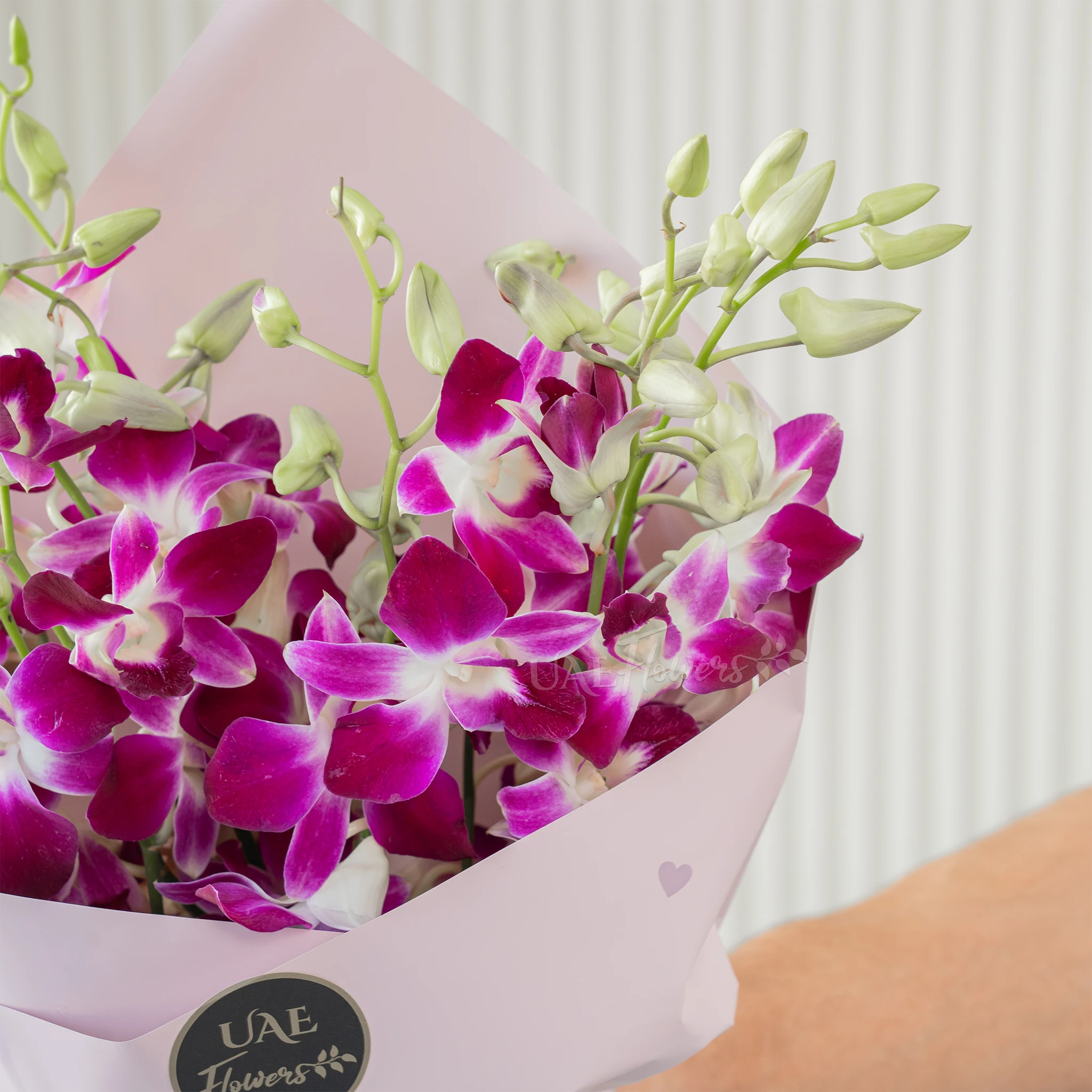 Bouquet of 10 purple orchids with fillers in a pink wrapping paper.