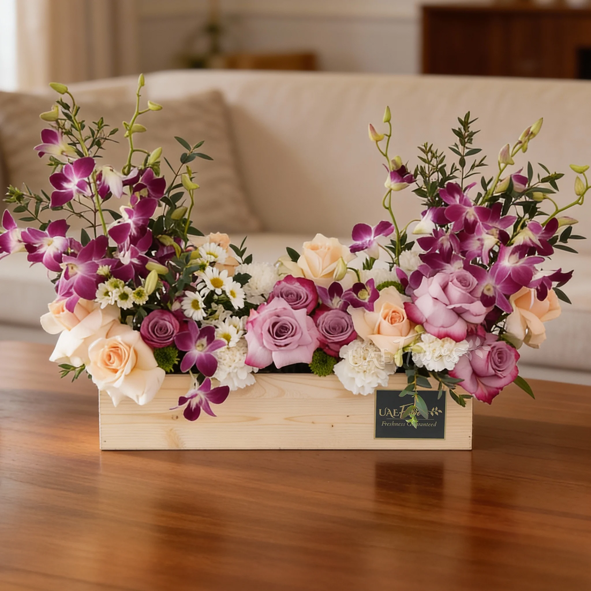 6 purple roses, 6 peach roses, 5 white carnations, 2 white chrysanthemums and 6 purple orchids in a wooden tray.