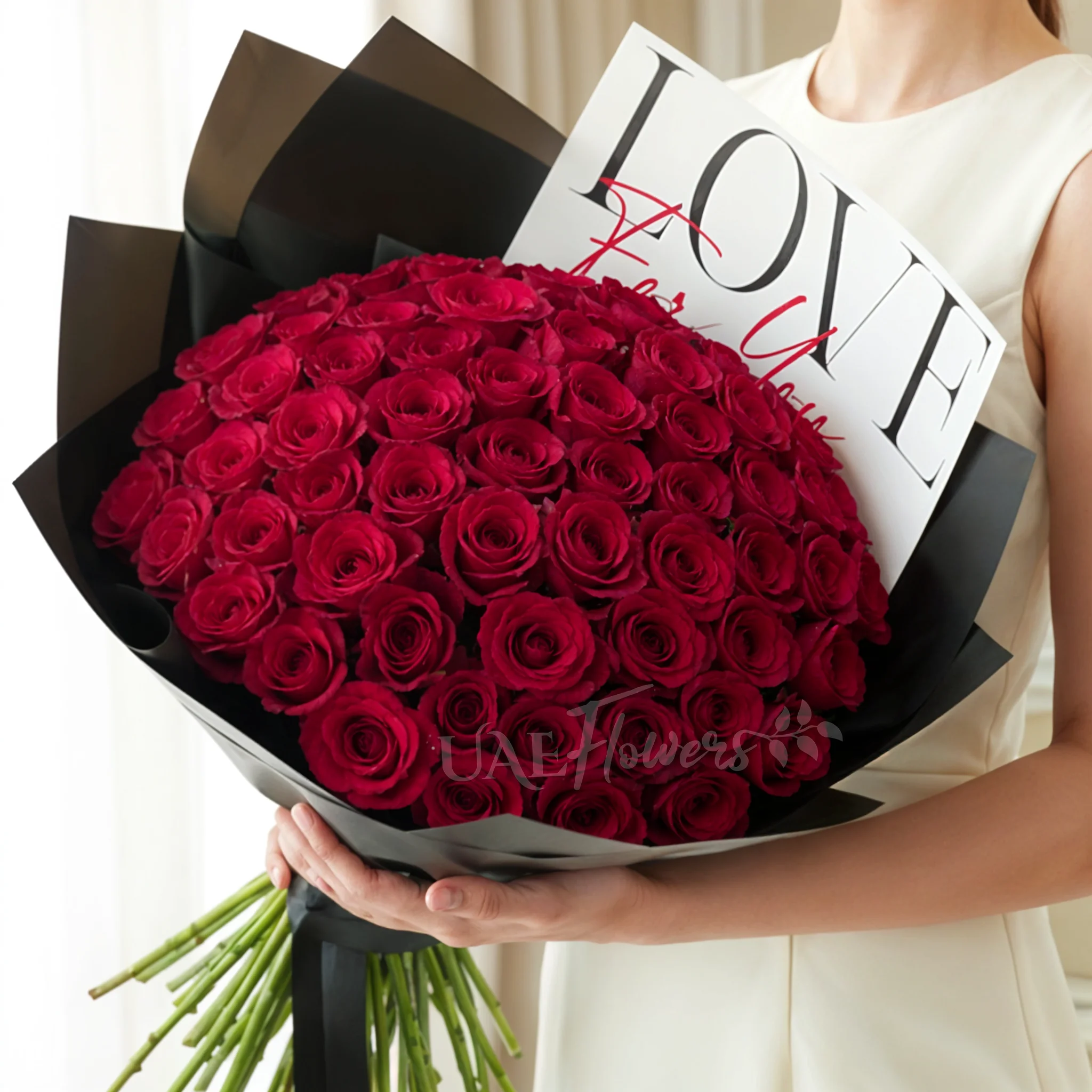 50 red roses with green fillers in black wrapping with Love For You Paper tied with black ribbons.