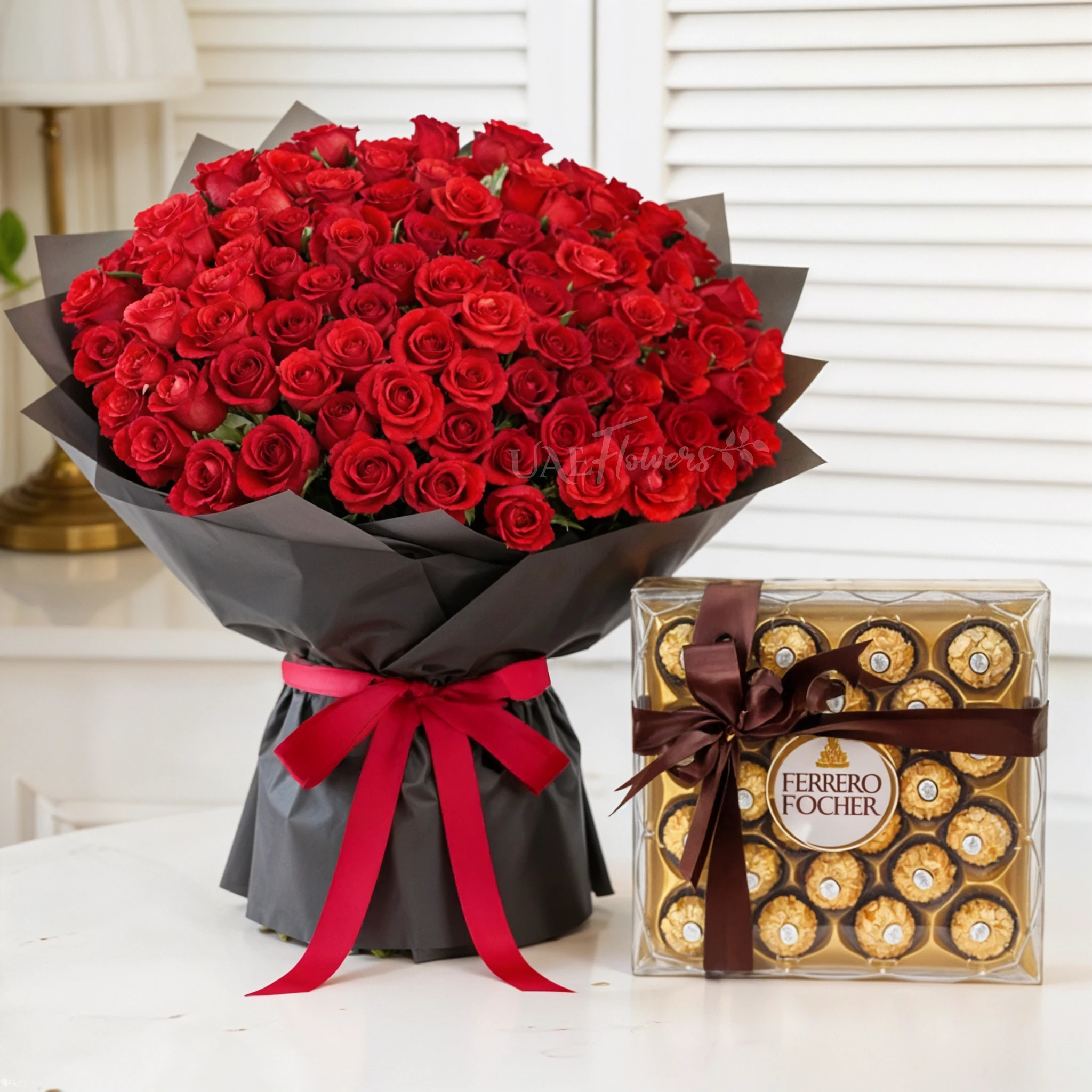 Bouquet of 100 red roses with green fillers in black wrapping and 24pcs Ferrero rocher chocolate.