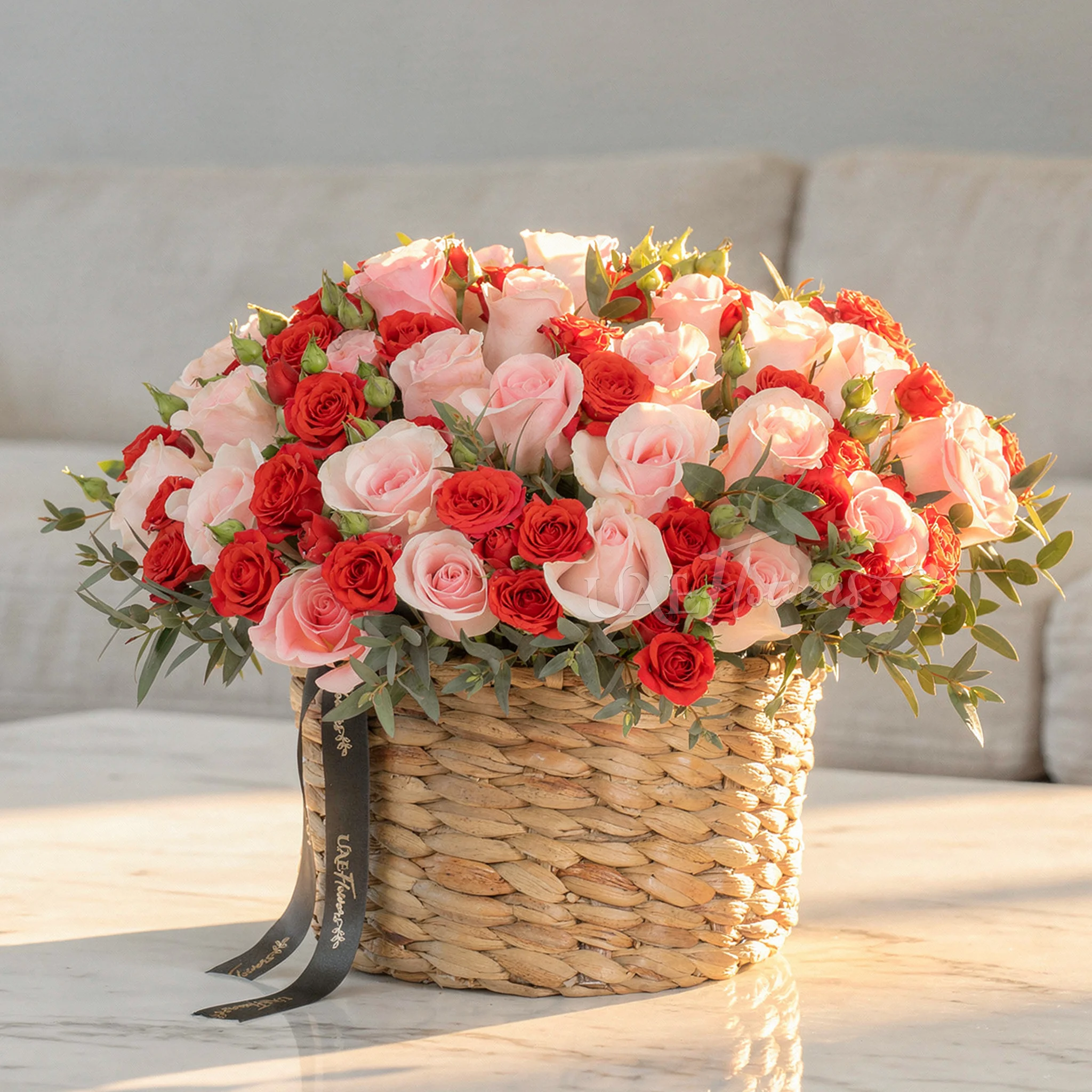 25 pink roses and 12 red spray roses with green fillers in a round basket.