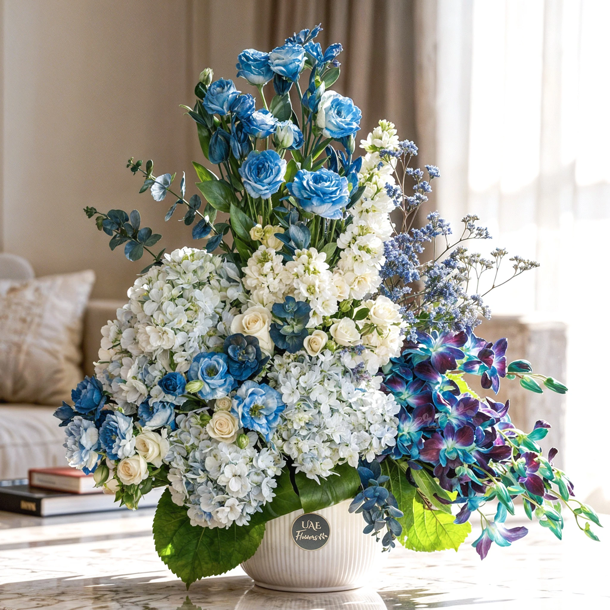 An arrangement of 10 white lisinathus, 5 white matthiola, 10 blue orchids, 5 white roses, 10 white spray roses and 3 blue hydrangeas with eucalyptus leaf and Limonium fillers in a ceramic pot.