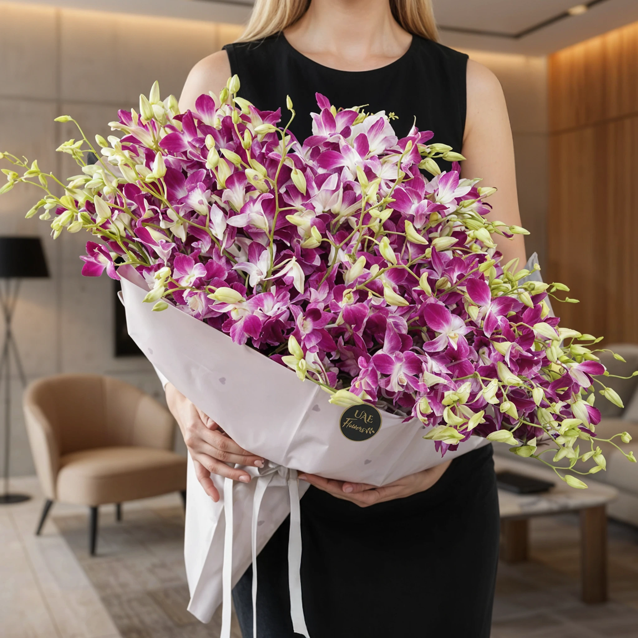 Bouquet of 100 purple orchids with fillers in a pink wrapping paper.