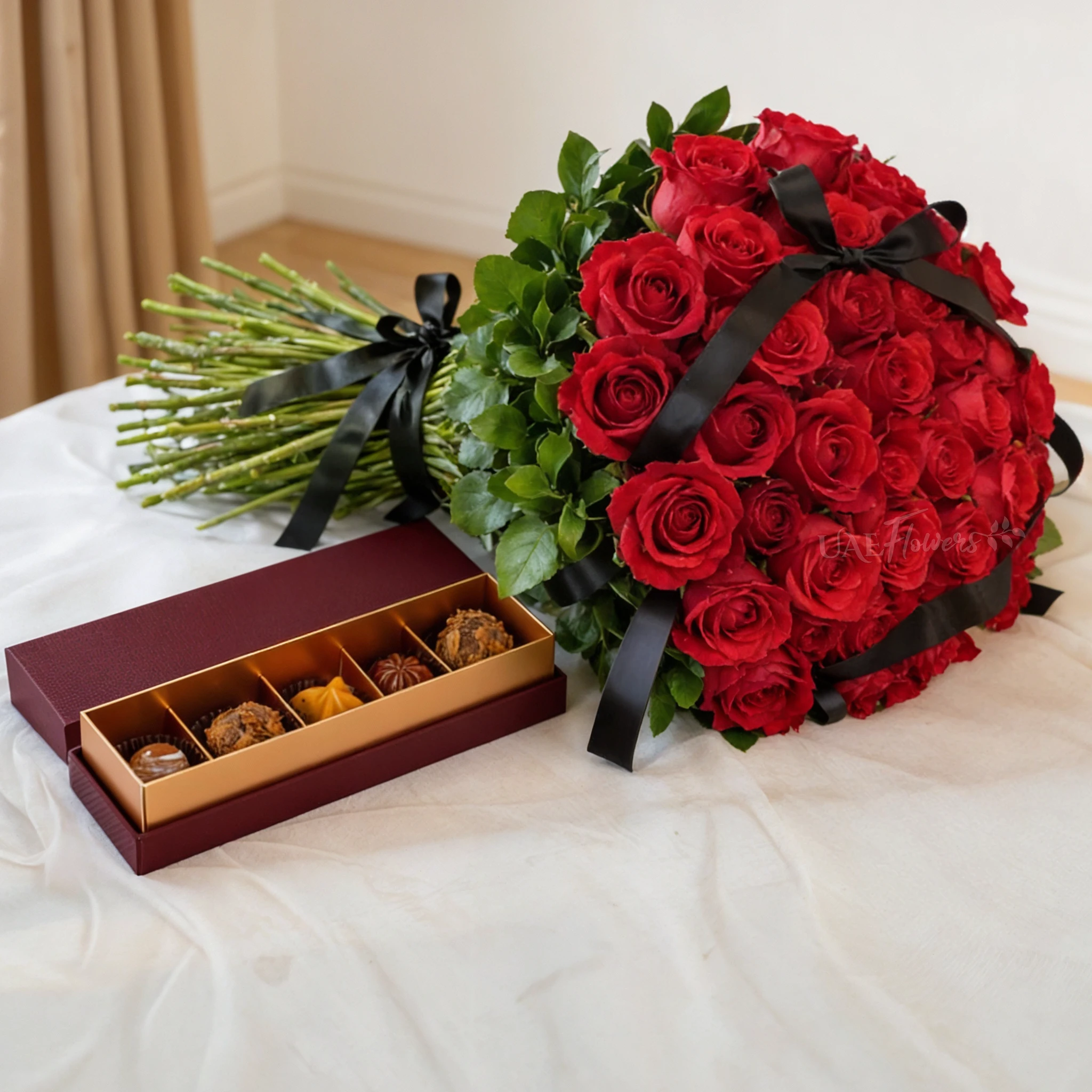Hand bouquet of 50 red roses with green fillers tied with black ribbon and 6 Pcs Pistache Petite Indulgence Chocolate Box.