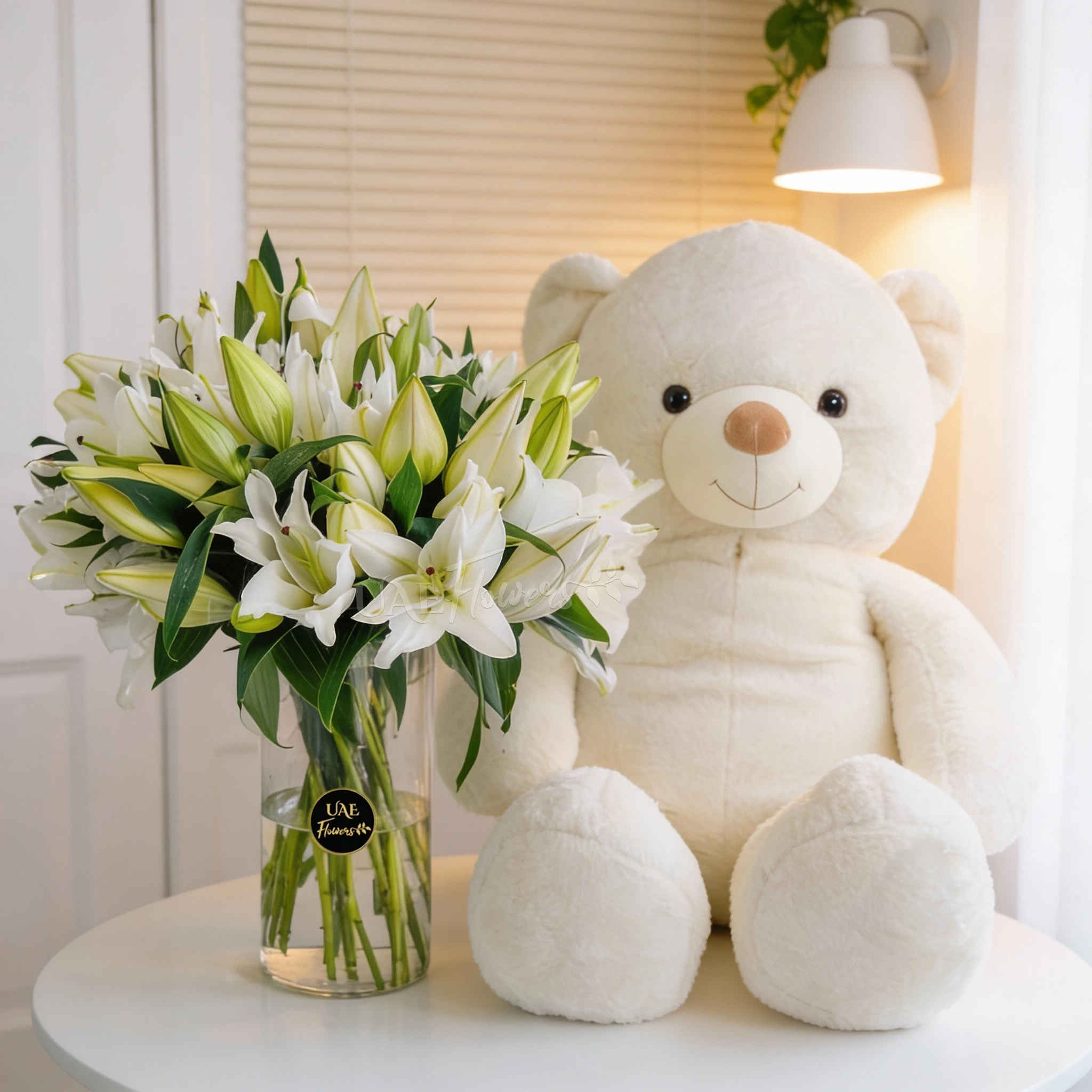15 white lilies with green fillers in glass vase and jumbo white teddy bear.