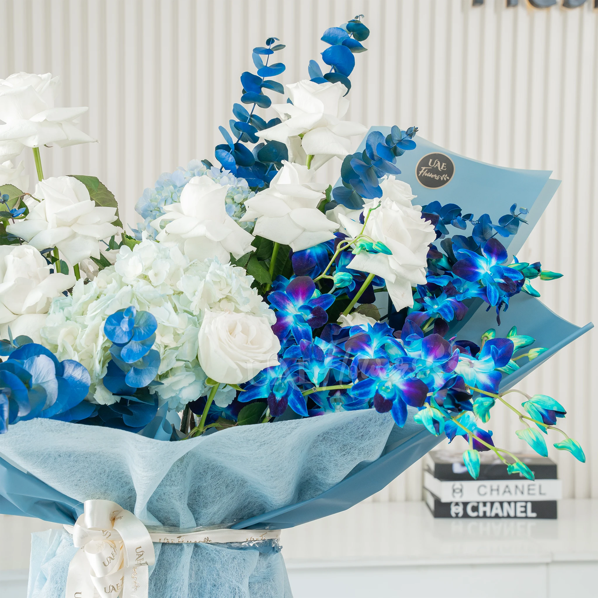 Bouquet of blue hydrangeas, white roses, and blue orchids wrapped in blue paper, a serene floral arrangement for special celebrations.