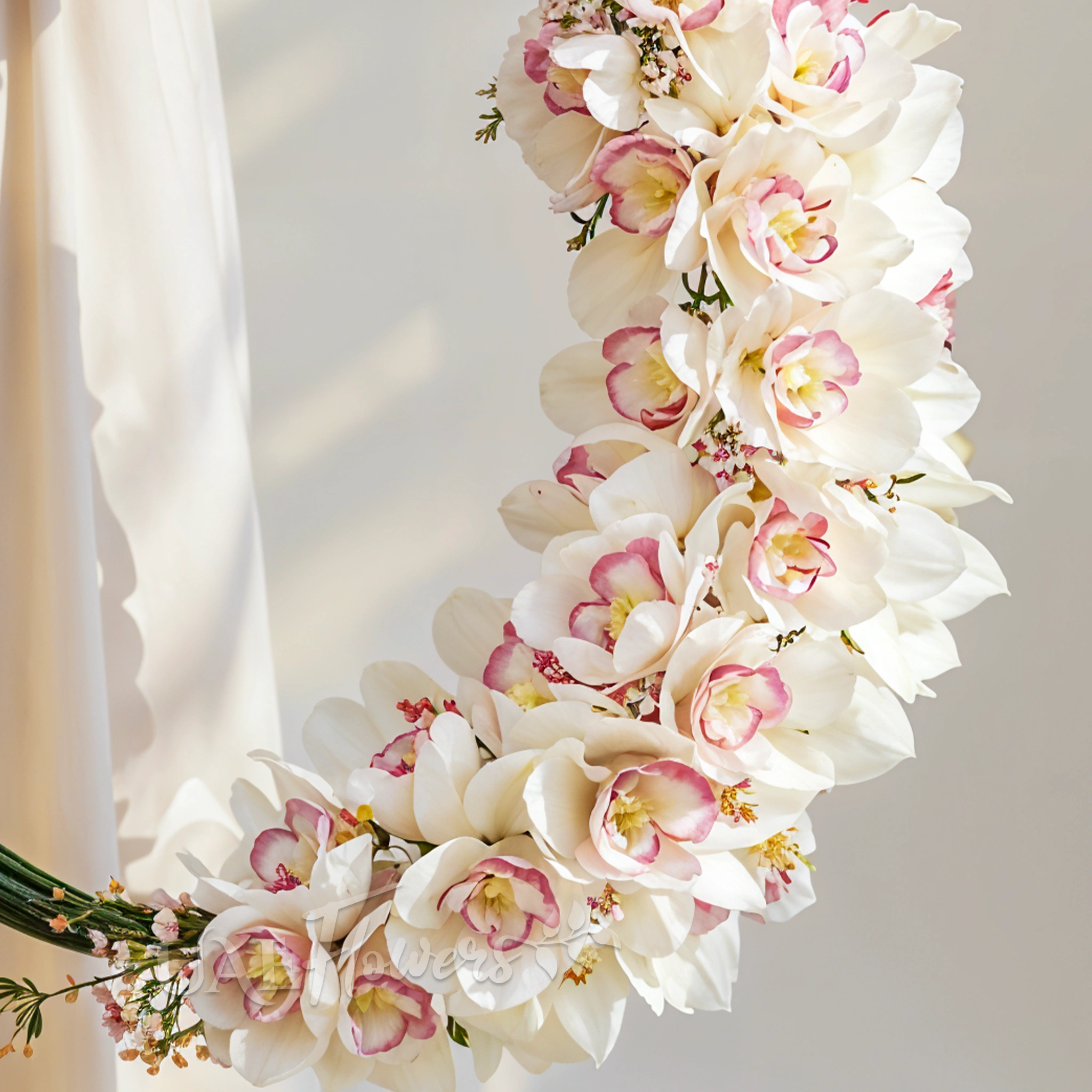 Bridal hand-tied round arrangement of 3 stems of white cymbidium orchids and 3 bundles of steel grass.