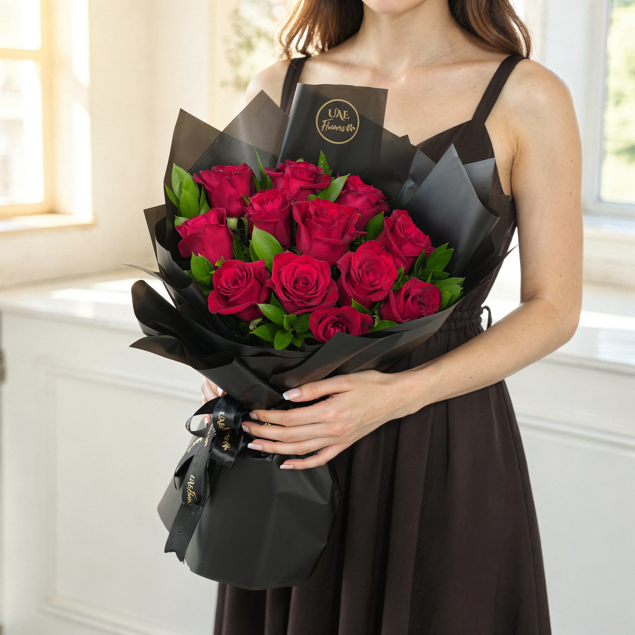 Bouquet of 12 red roses with green fillers in black wrapping paper.