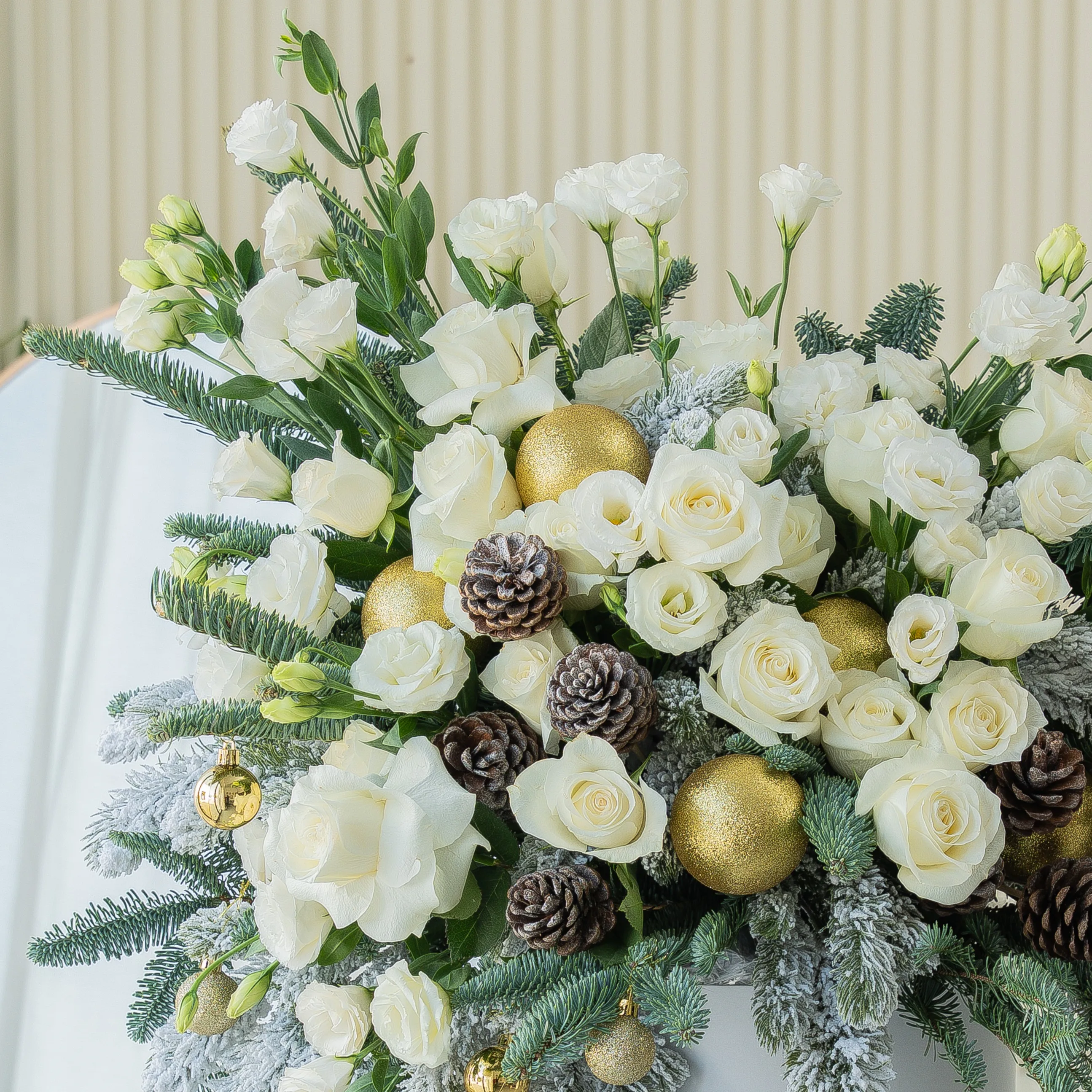 luxury white christmas flower arrangement with roses pinecones and frosted greens