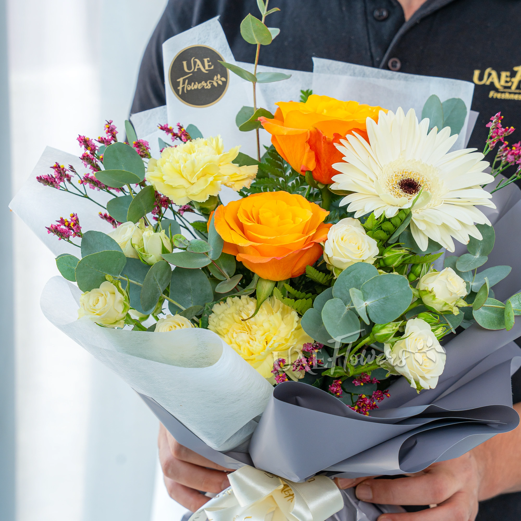 Bouquet of 2 Orange Roses, 2 Yellow Carnations, 2 white spray roses with eucalyptus leaves and limonium in nice wrapping.