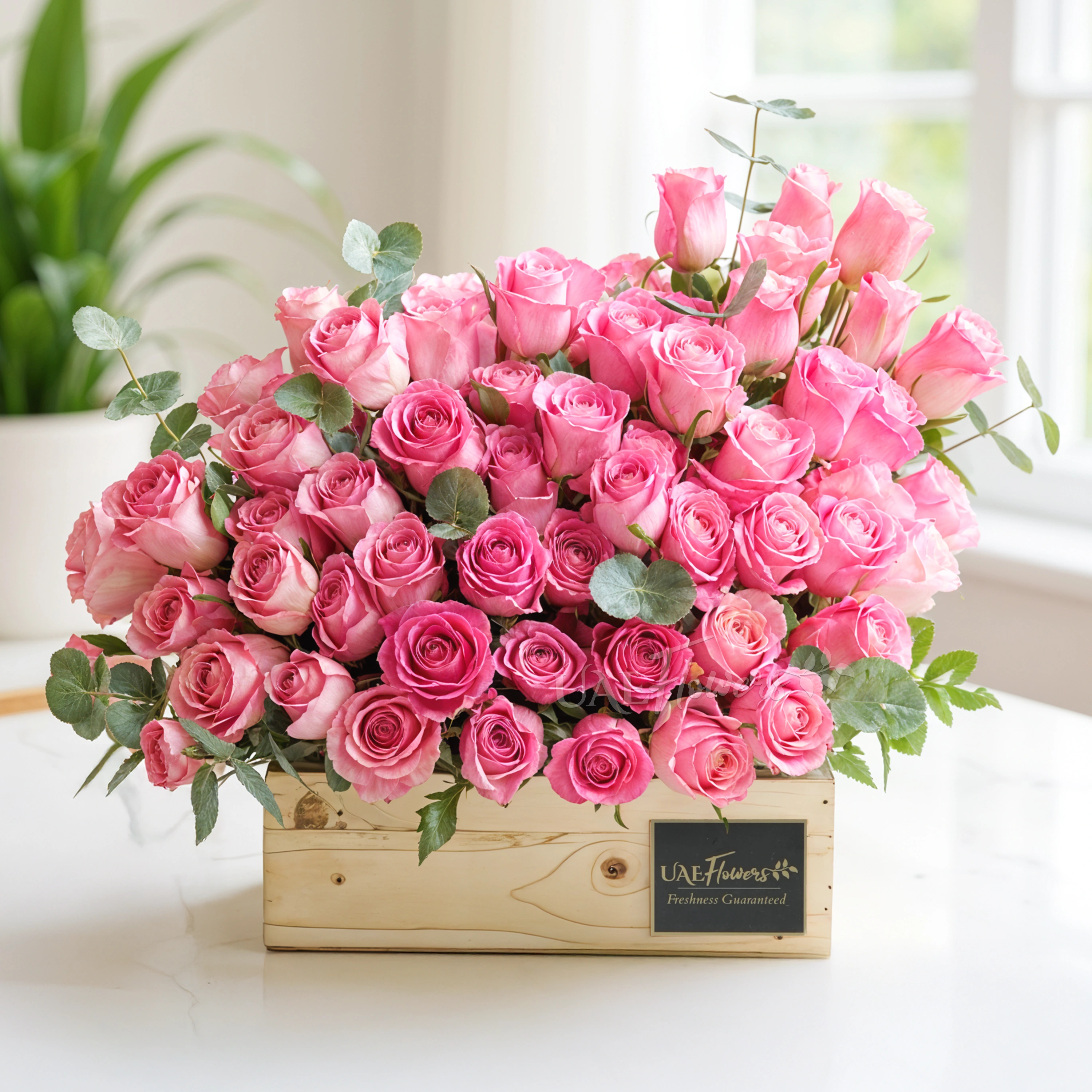 50 Hermosa pink roses in a wooden tray with eucalyptus leaves.