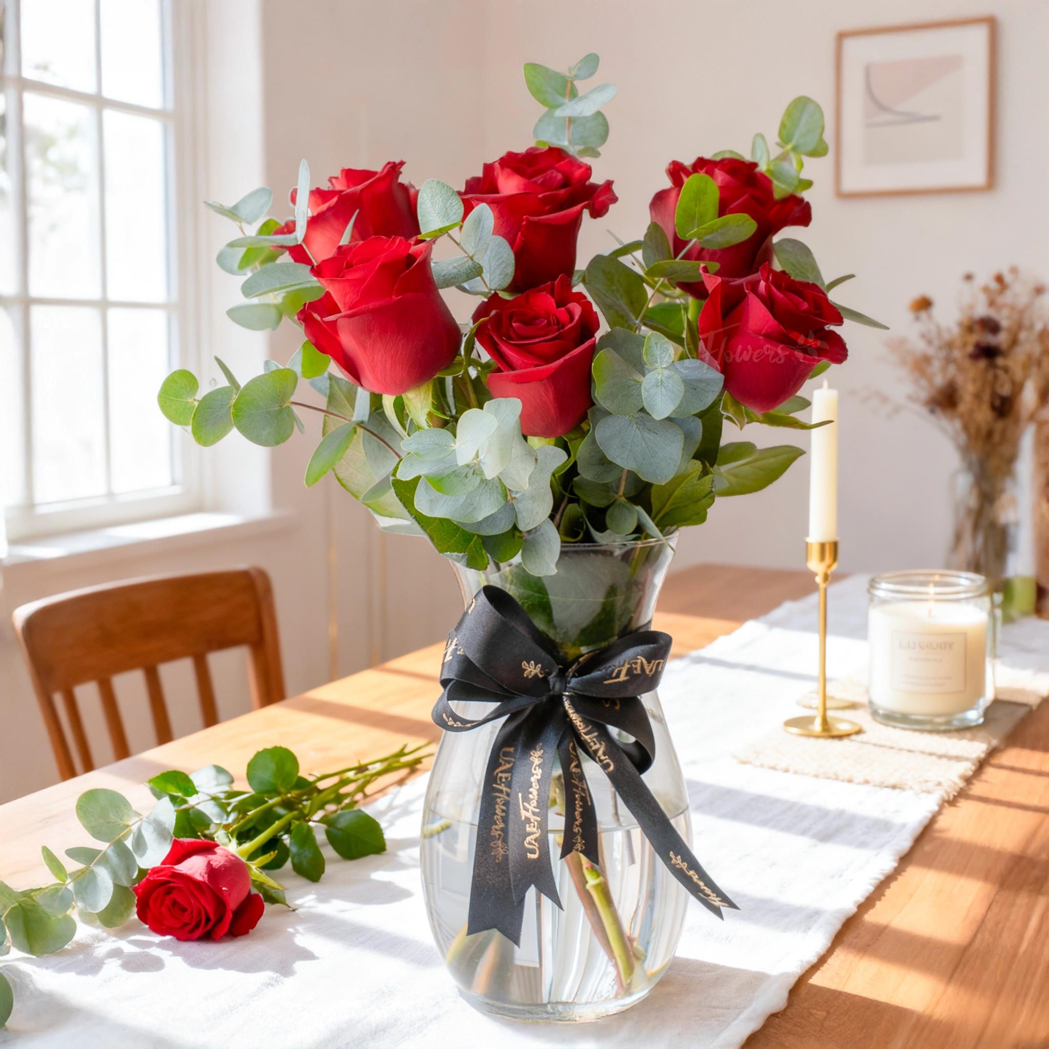 6 red roses arranged in a glass vase with eucalyptus
