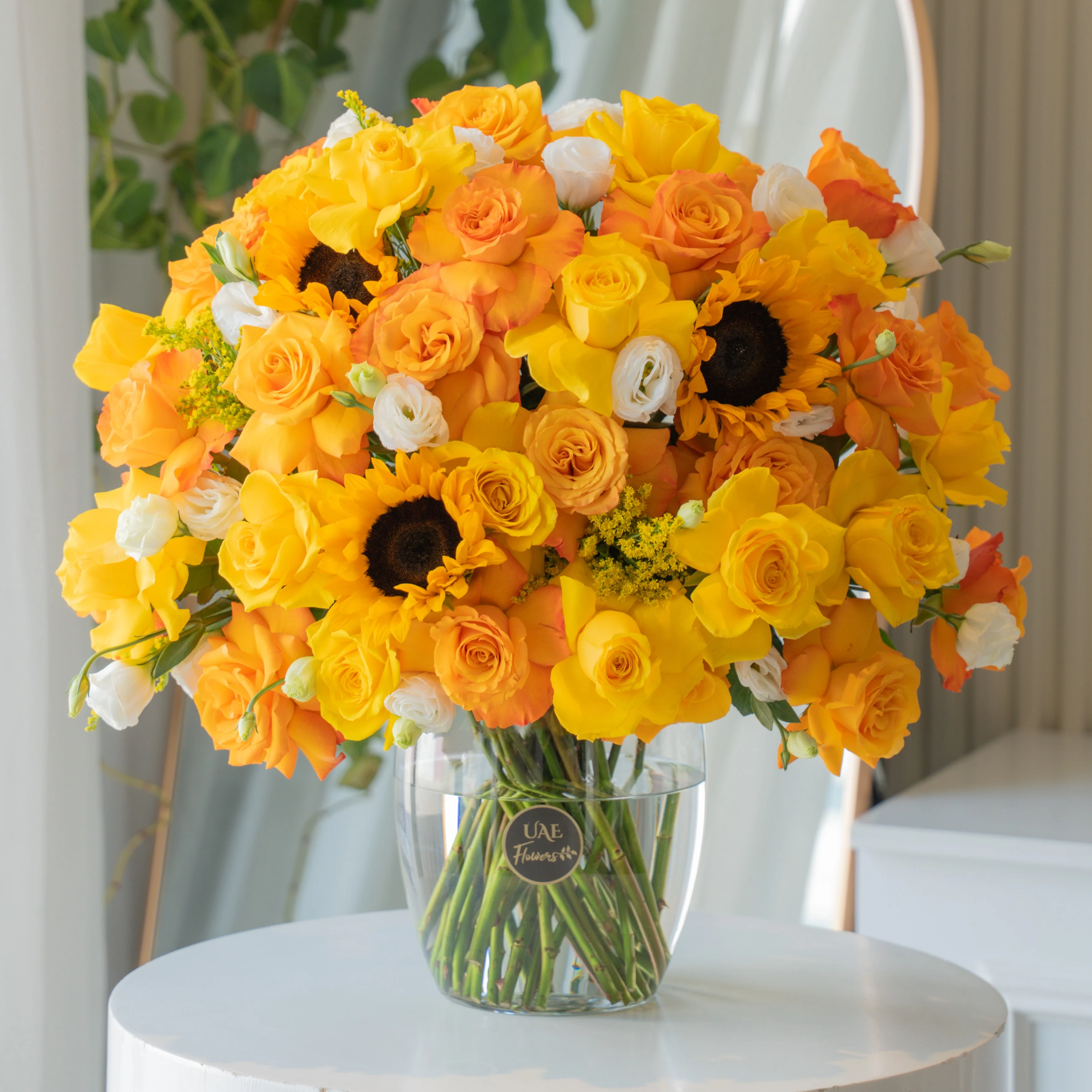 Yellow, orange, and white roses with sunflowers in glass vase for Diwali by UAE Flowers Dubai