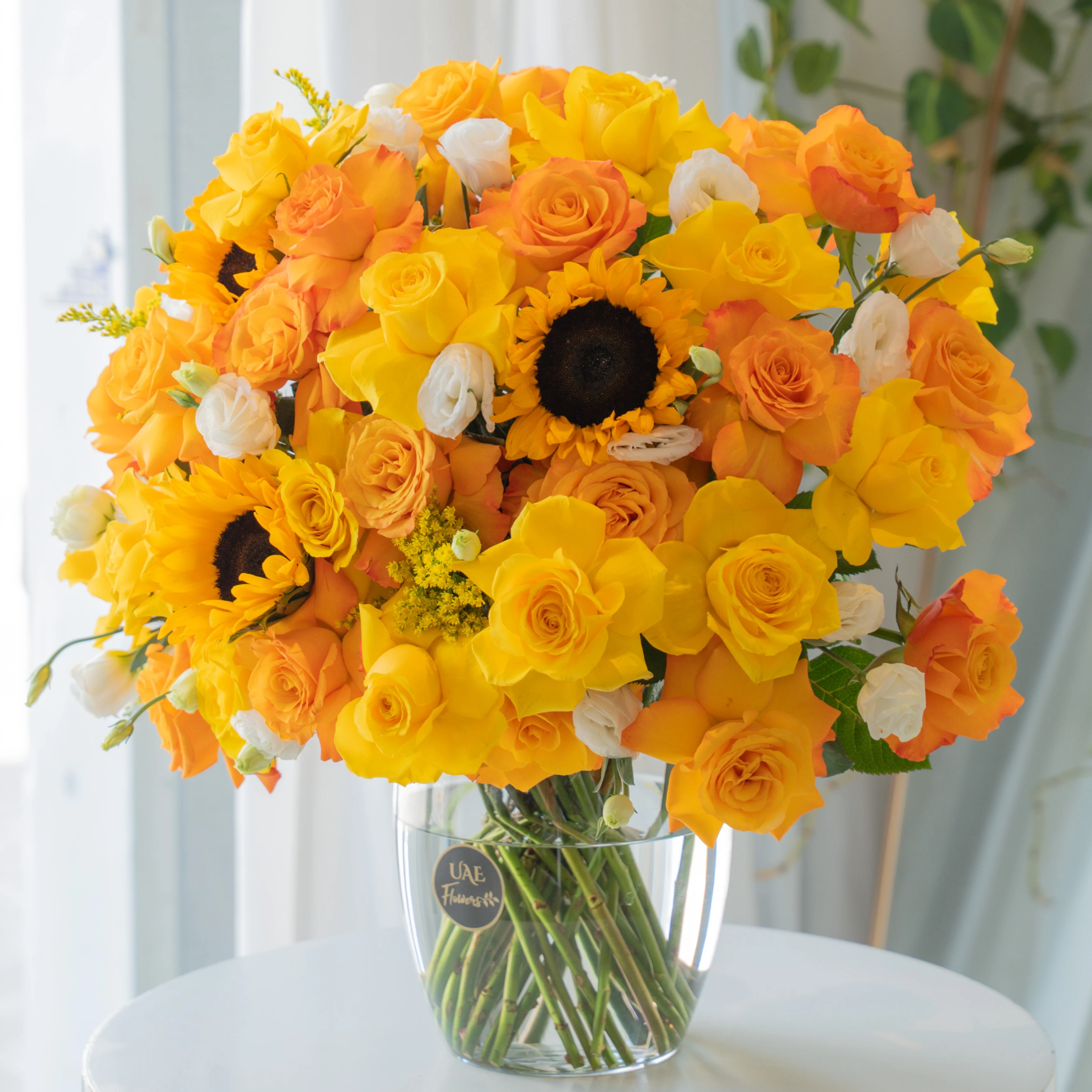 Yellow, orange, and white roses with sunflowers in glass vase for Diwali by UAE Flowers Dubai