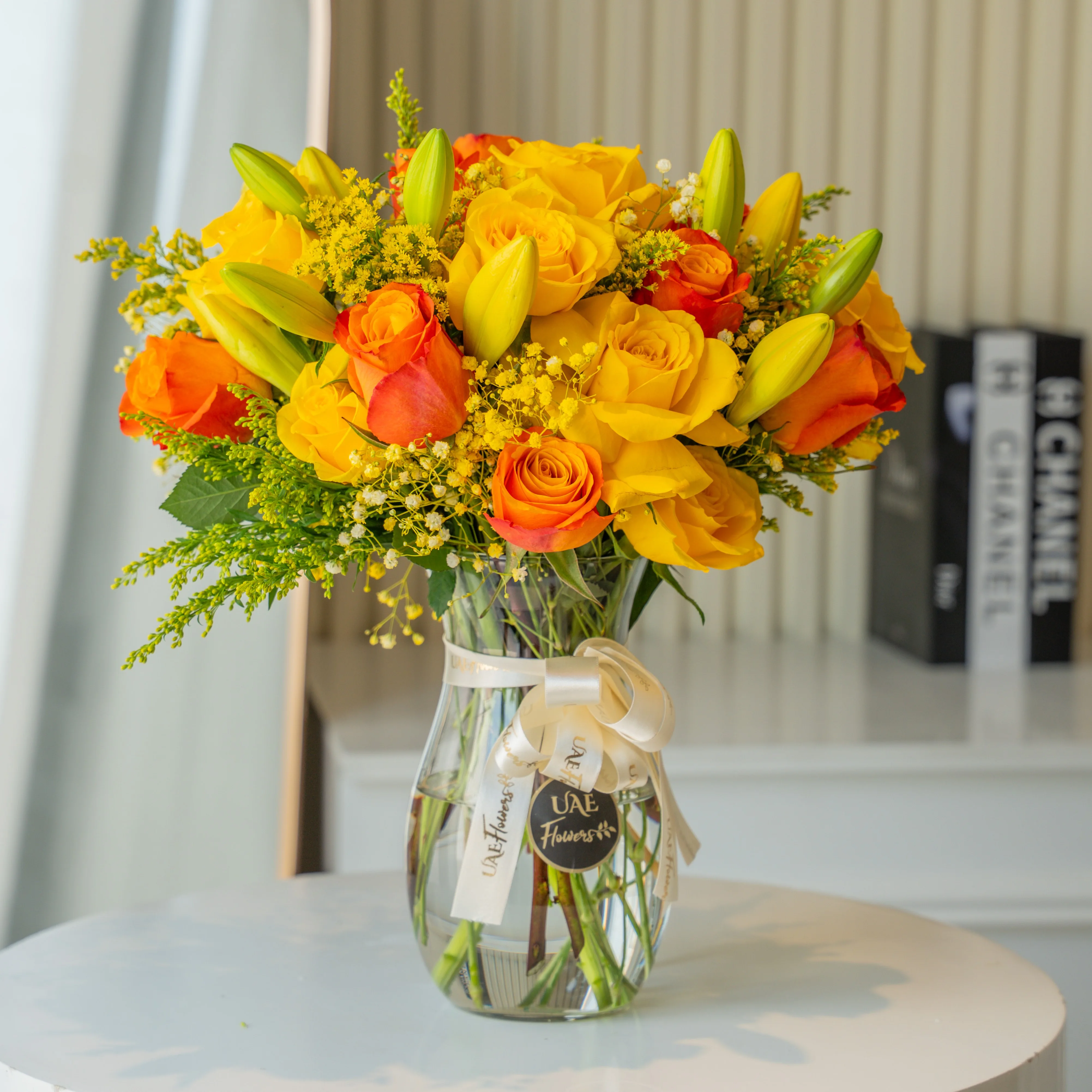Yellow and orange roses with lilies in glass vase for Diwali by UAE Flowers Dubai