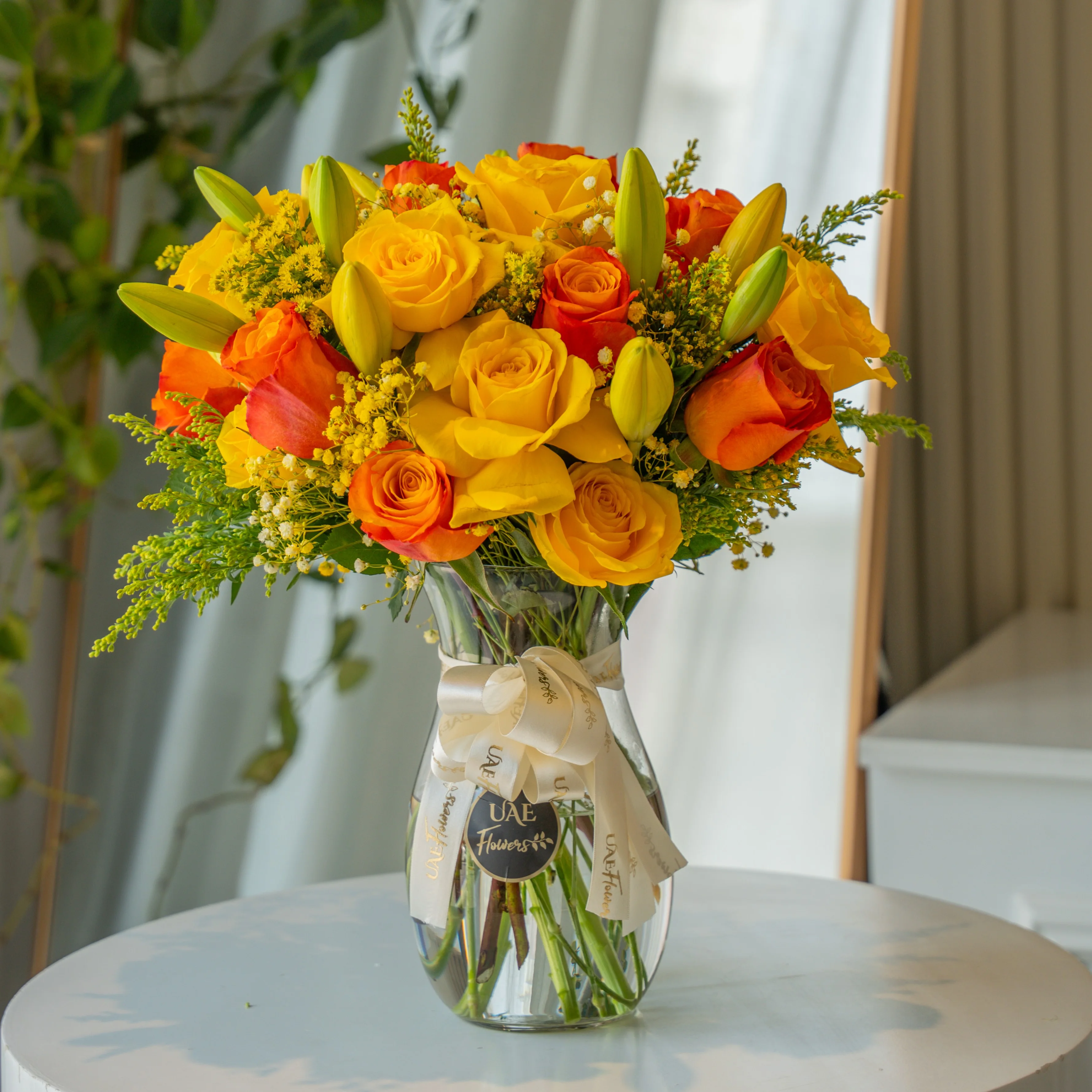 Yellow and orange roses with lilies in glass vase for Diwali by UAE Flowers Dubai