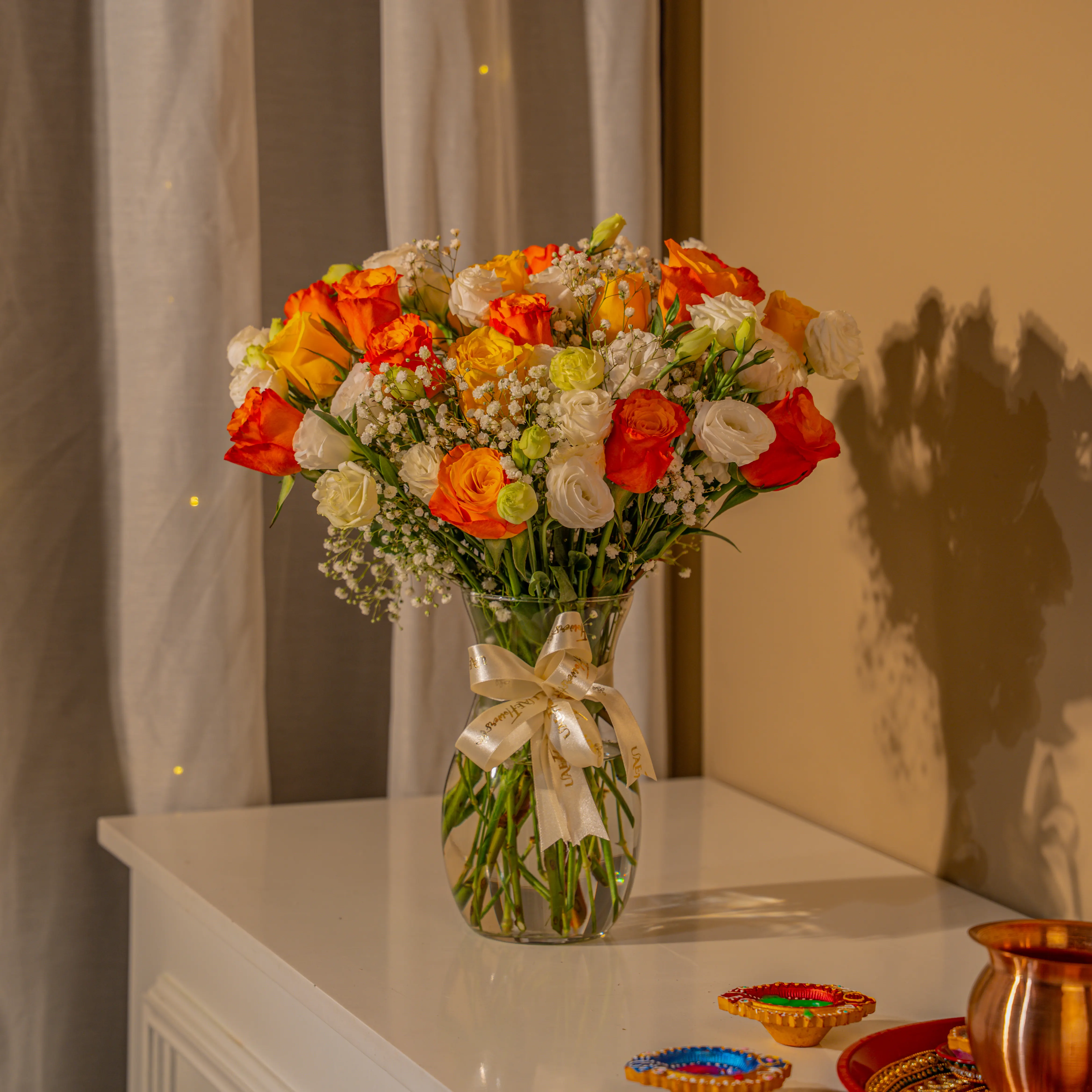 Orange, yellow, and white roses in glass vase for Diwali by UAE Flowers Dubai