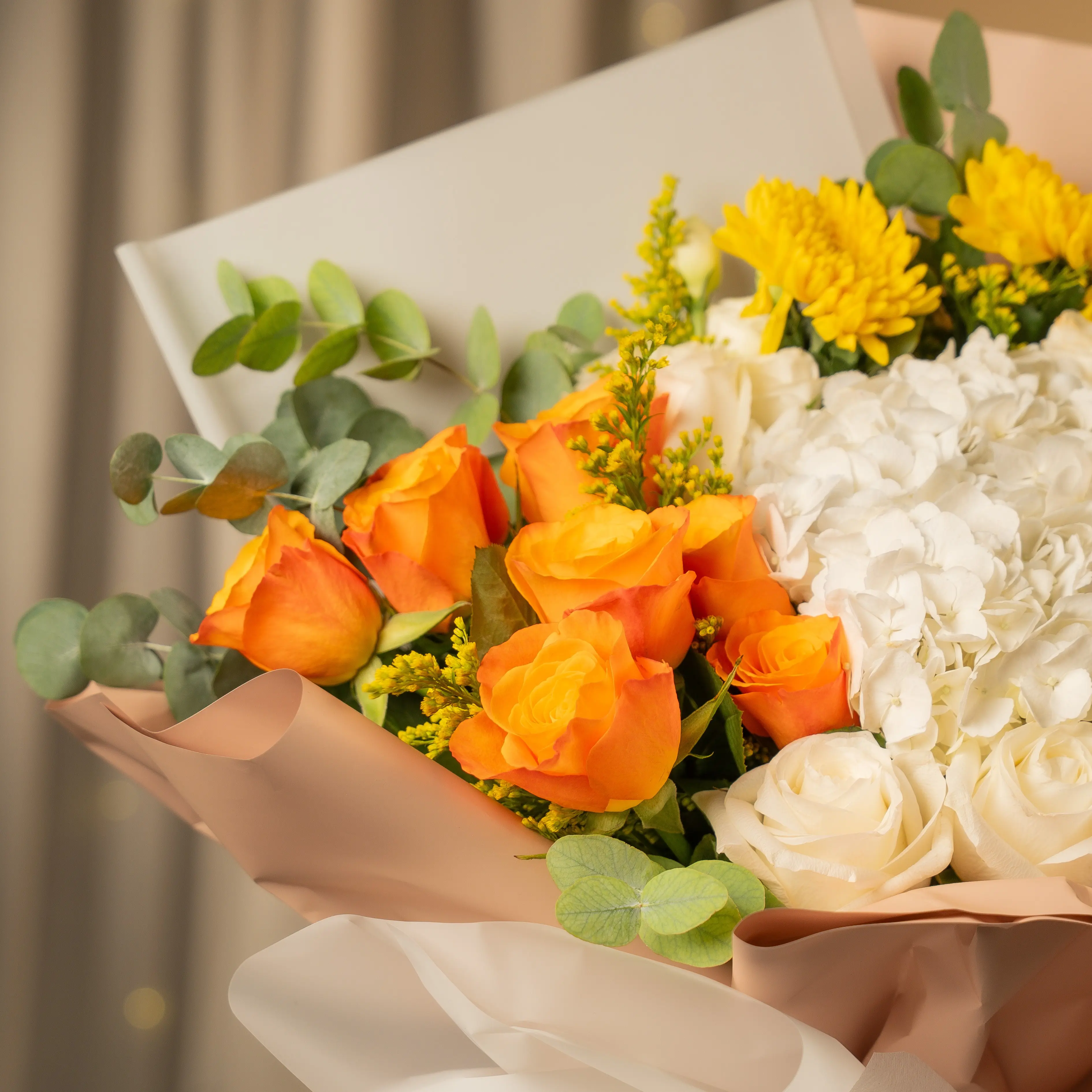 Orange, yellow, and white flower bouquet wrapped in elegant paper for Diwali by UAE Flowers Dubai