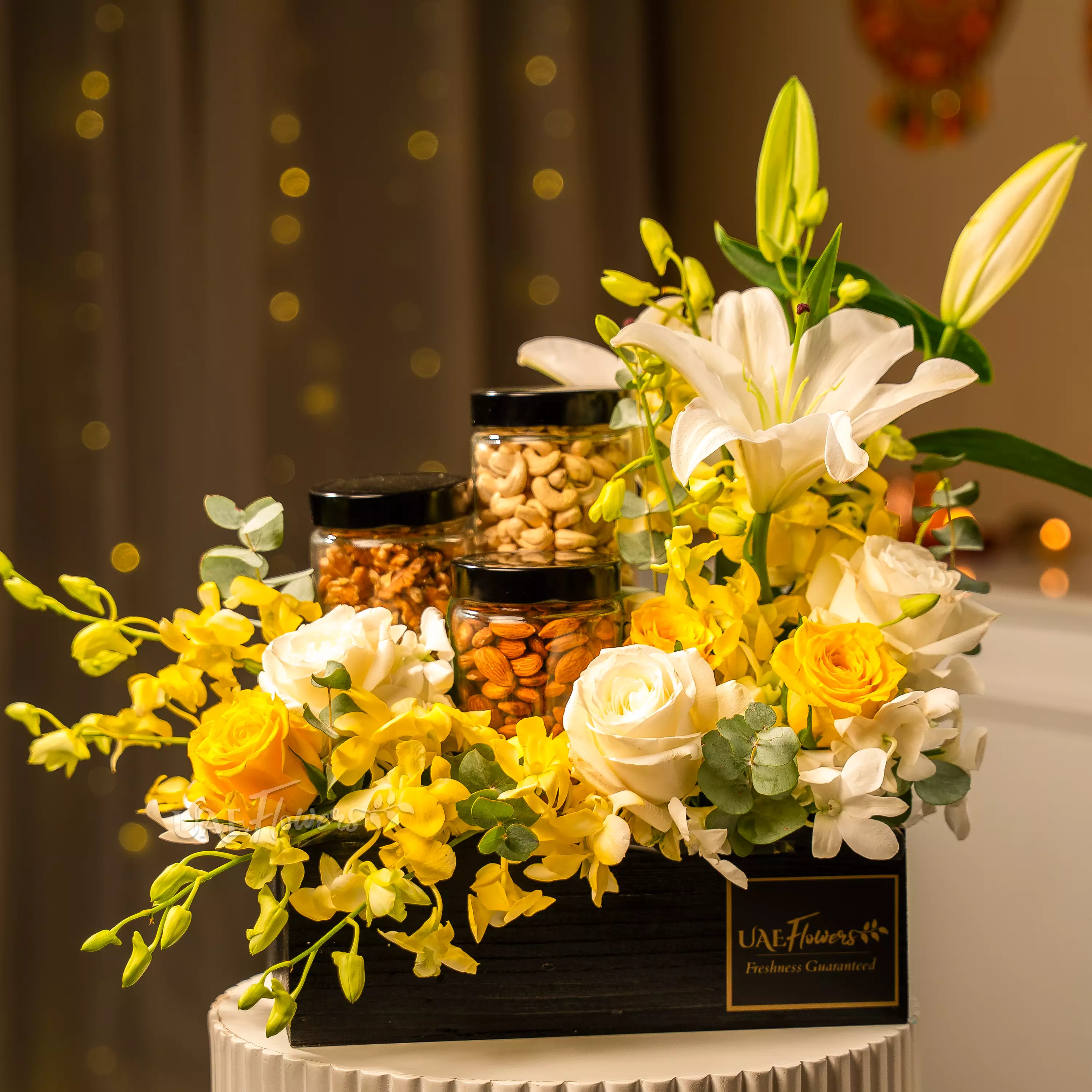 Yellow and white flowers with dry fruit jars in Diwali hamper by UAE Flowers Dubai