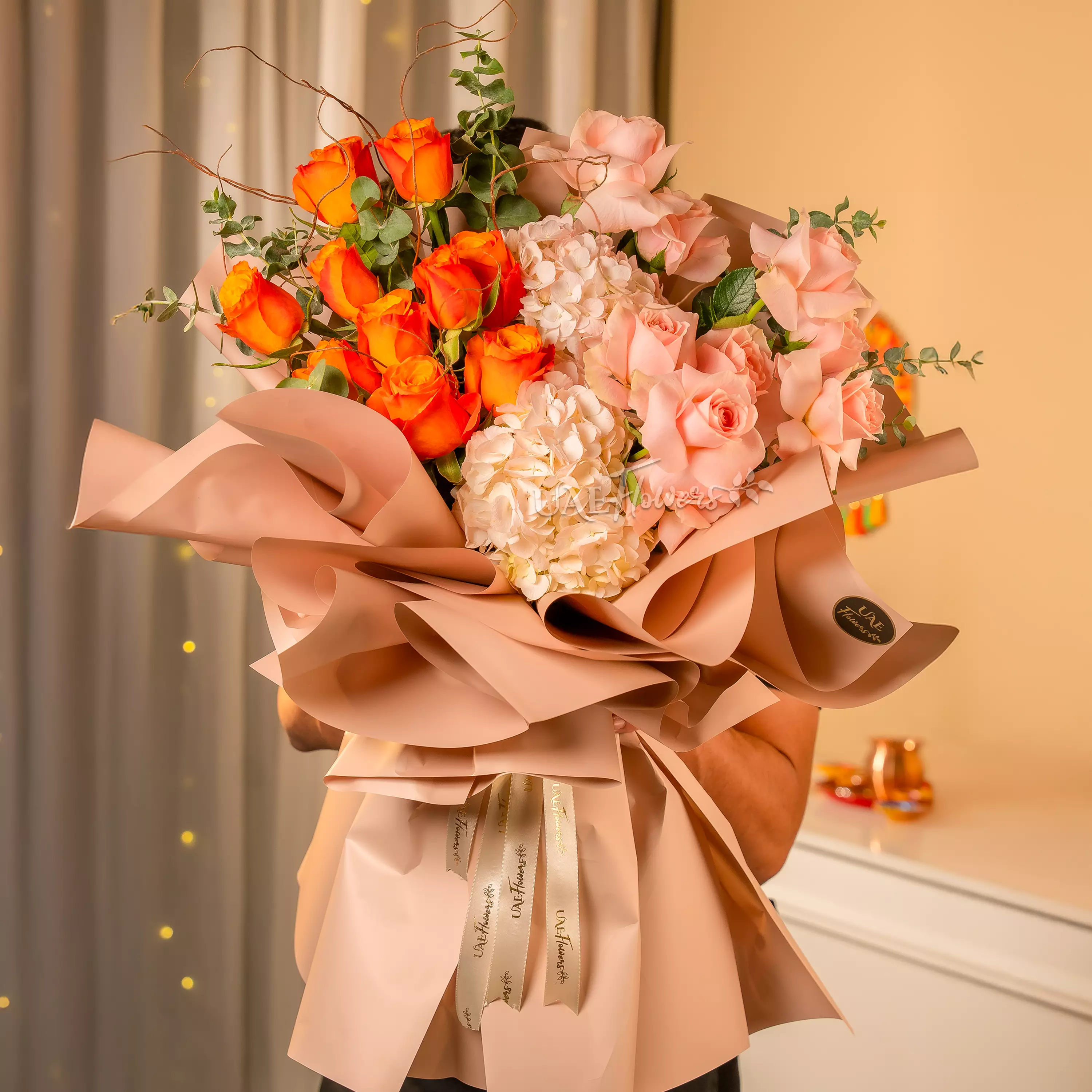 Man holding peach, pink, and orange rose bouquet for Diwali by UAE Flowers Dubai