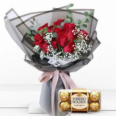 A bouquet of 12 red roses with fillers in black wrapping paper tied with pink ribbon and 16 pieces of ferrero rocher chocolate