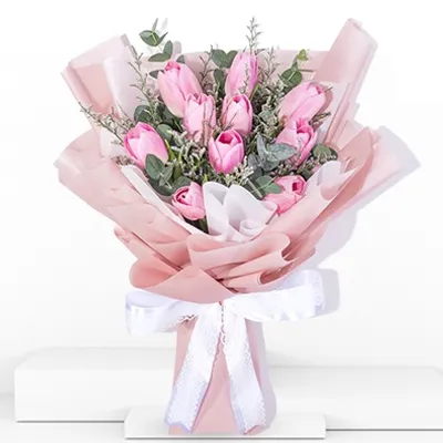 A bouquet of 10 pink tulips with fillers in pink wrapping paper tied with white ribbon