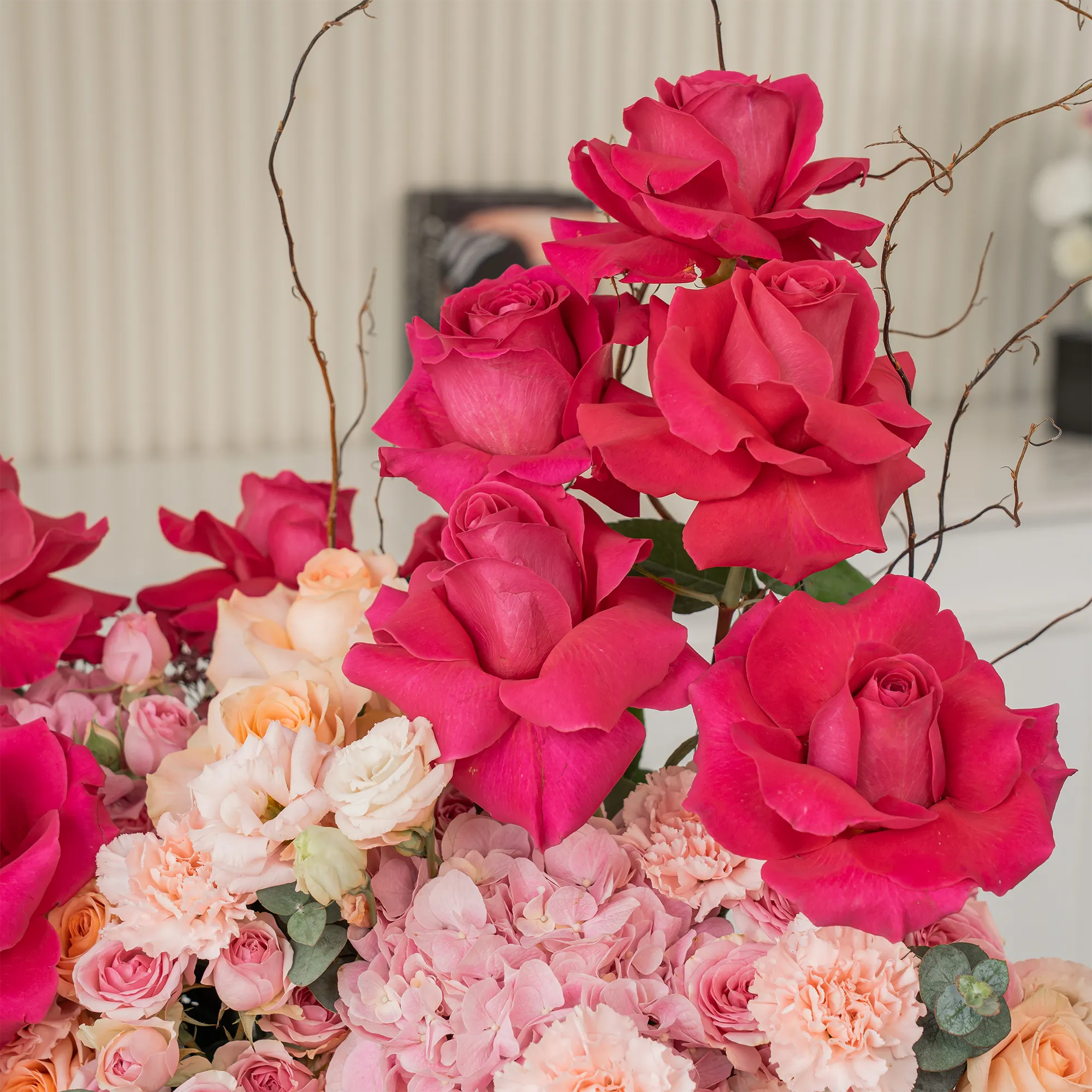 Arrangement of 10 fuchsia roses, 20 pink carnations, 20 pink spray roses, 20 peach roses and 2 pink hydrangeas with green fillers in a long black box.