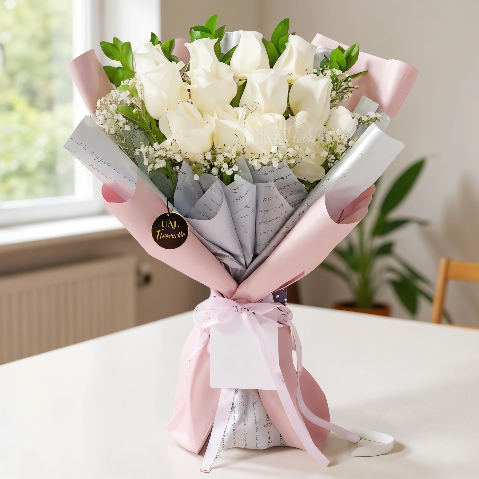 A bouquet of 12 white roses with fillers in a pink wrapping paper tied with pink ribbon