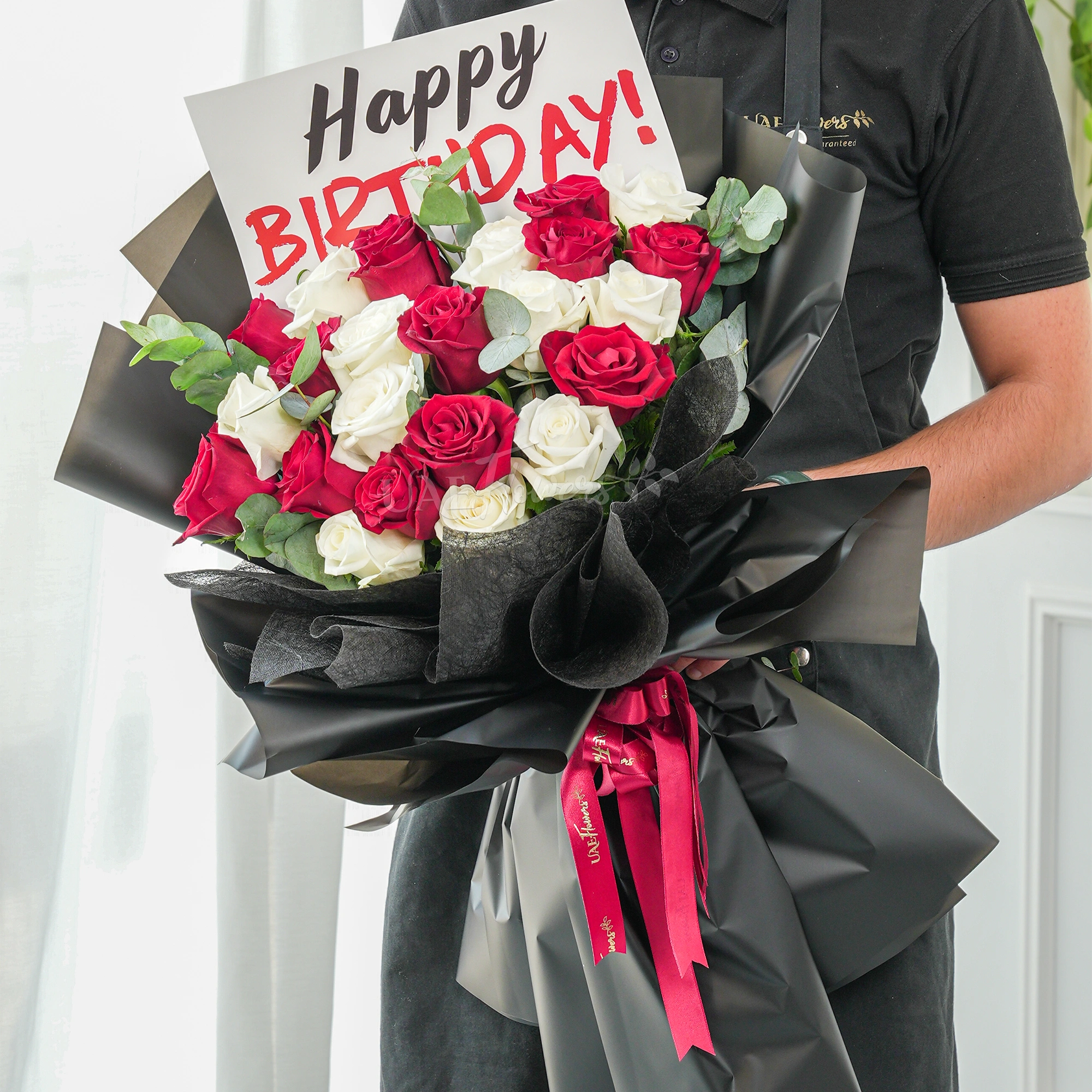 Bouquet of 20 red and white roses with green fillers in black wrapping with Happy Birthday Paper.