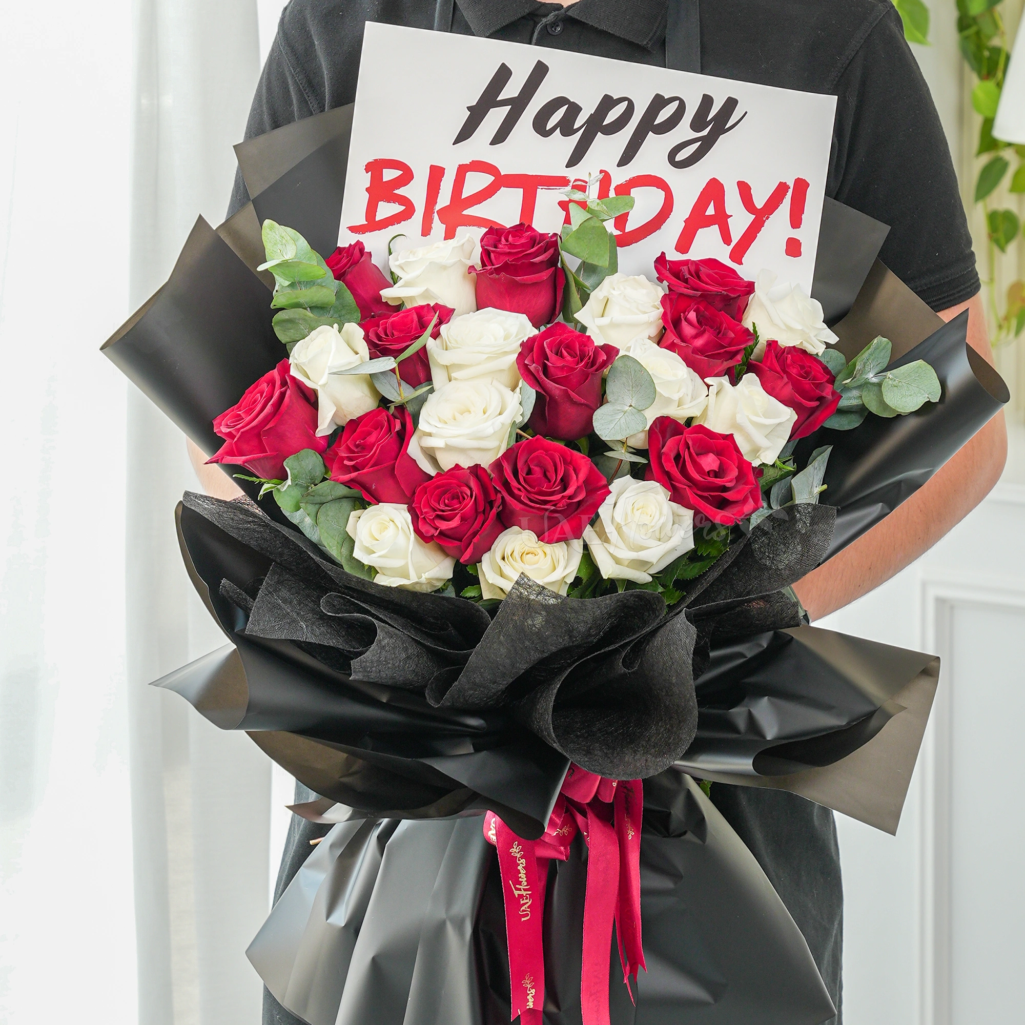 Bouquet of 20 red and white roses with green fillers in black wrapping with Happy Birthday Paper.